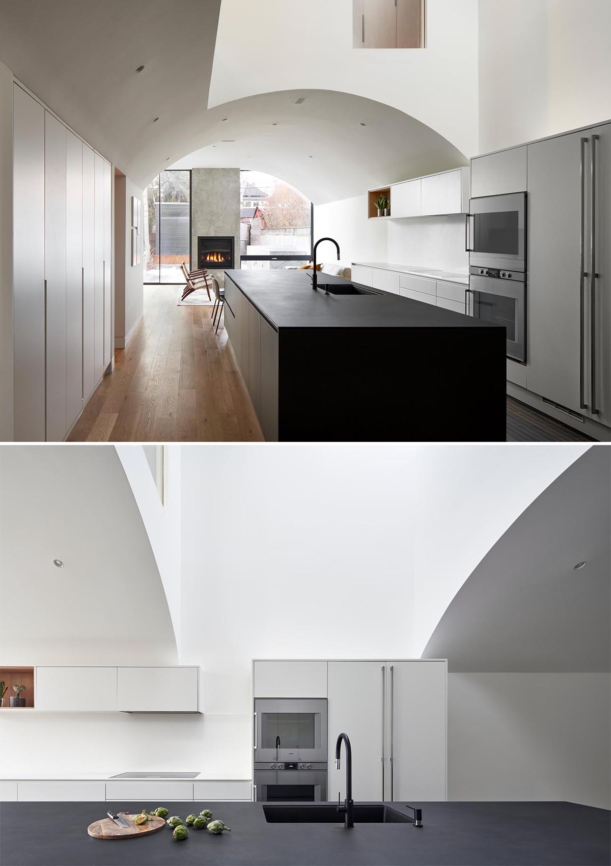 This kitchen, which has white minimalist cabinets that line the wall, and a matte blue kitchen island, also includes a more casual dining area by the living room.