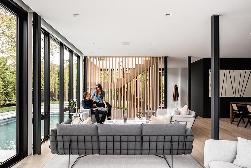 This modern home interior utilizes a simple material palette of blackened steel, light hardwood, and neutral colors, as shown in the open plan main floor of the home.