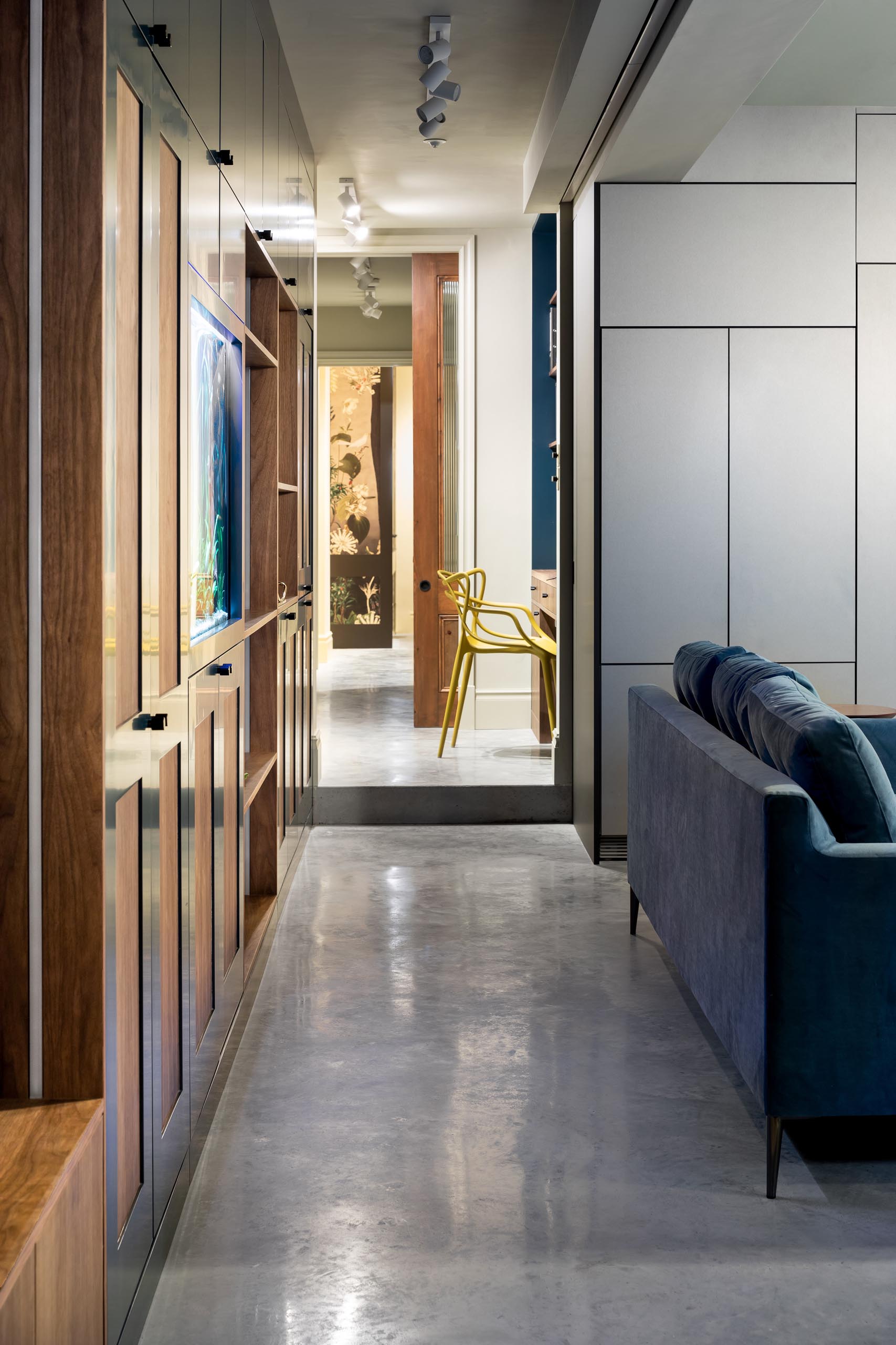 A modern hallway with polished concrete floors and lined with cabinetry and a home office.