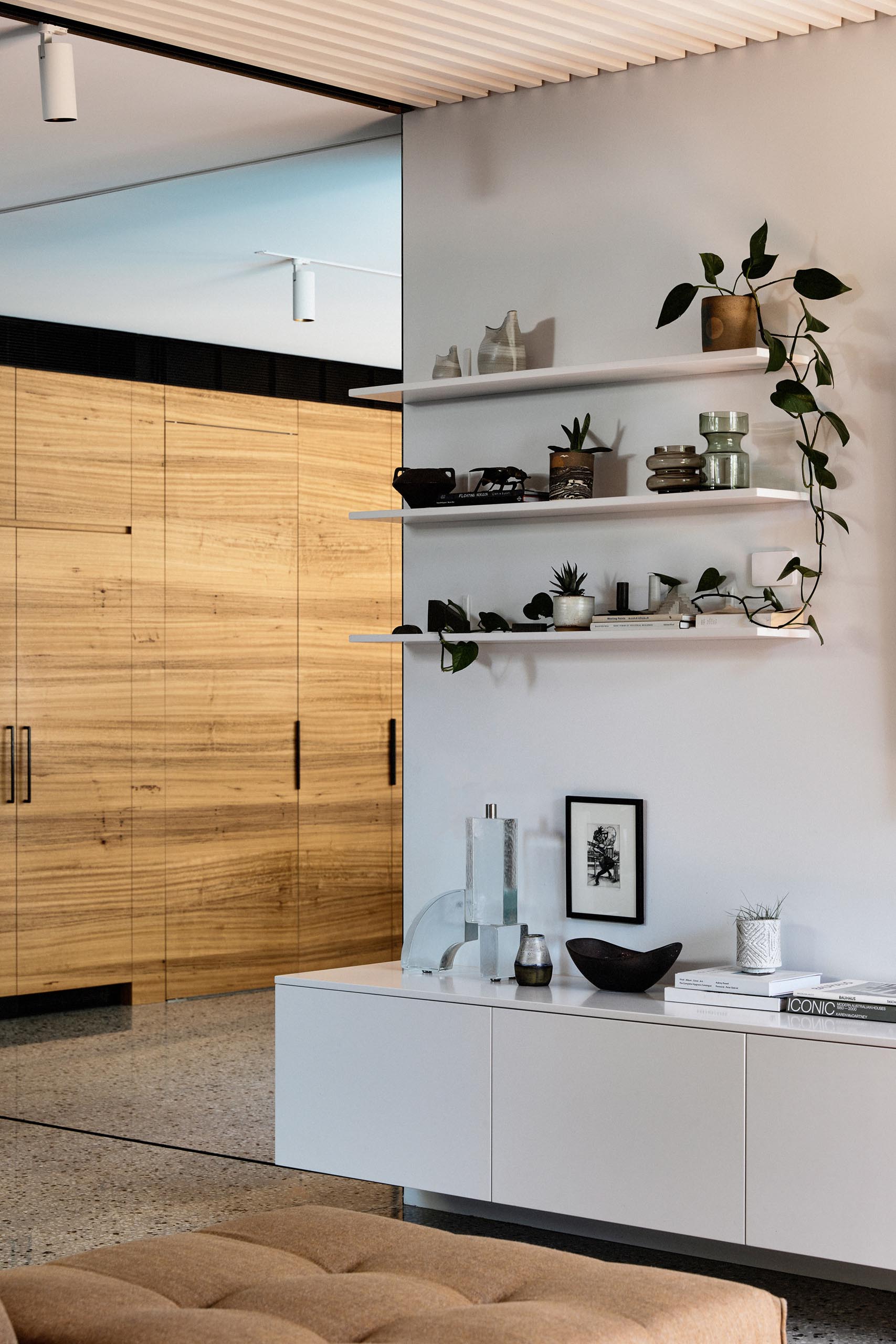 A low television console and floating white shelves that match the ceiling.