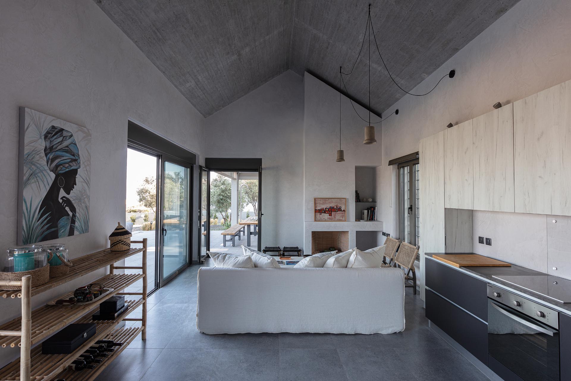 A modern open plan living room and kitchen with a pitched ceiling and doors that open to a terrace.