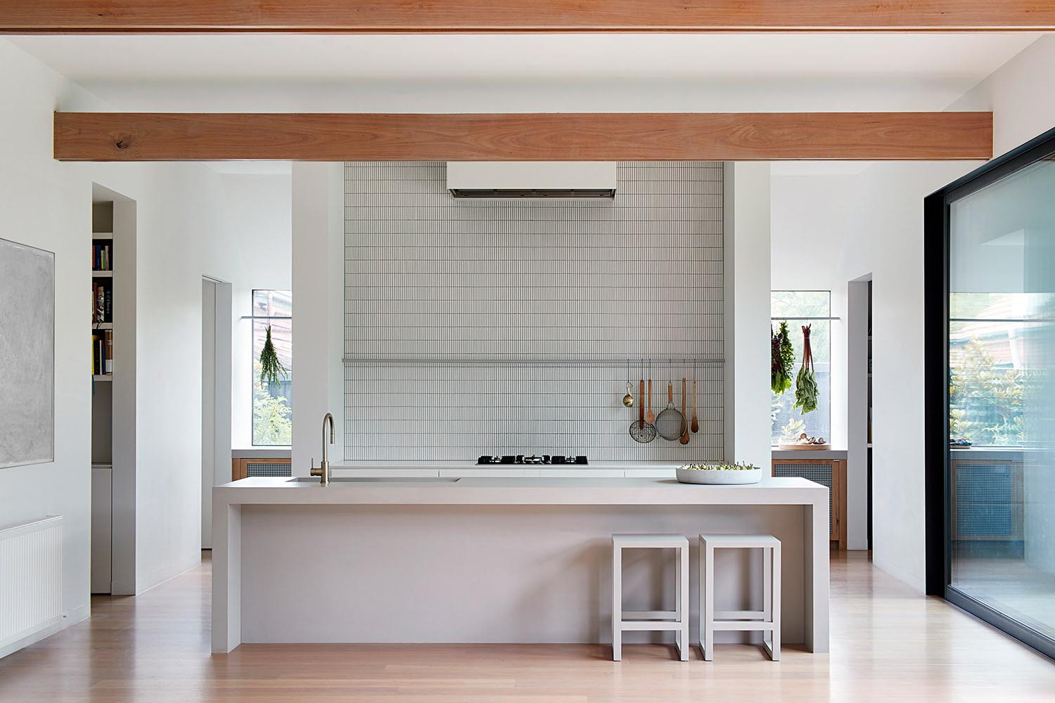 A minimalist kitchen with an island and tiled wall.