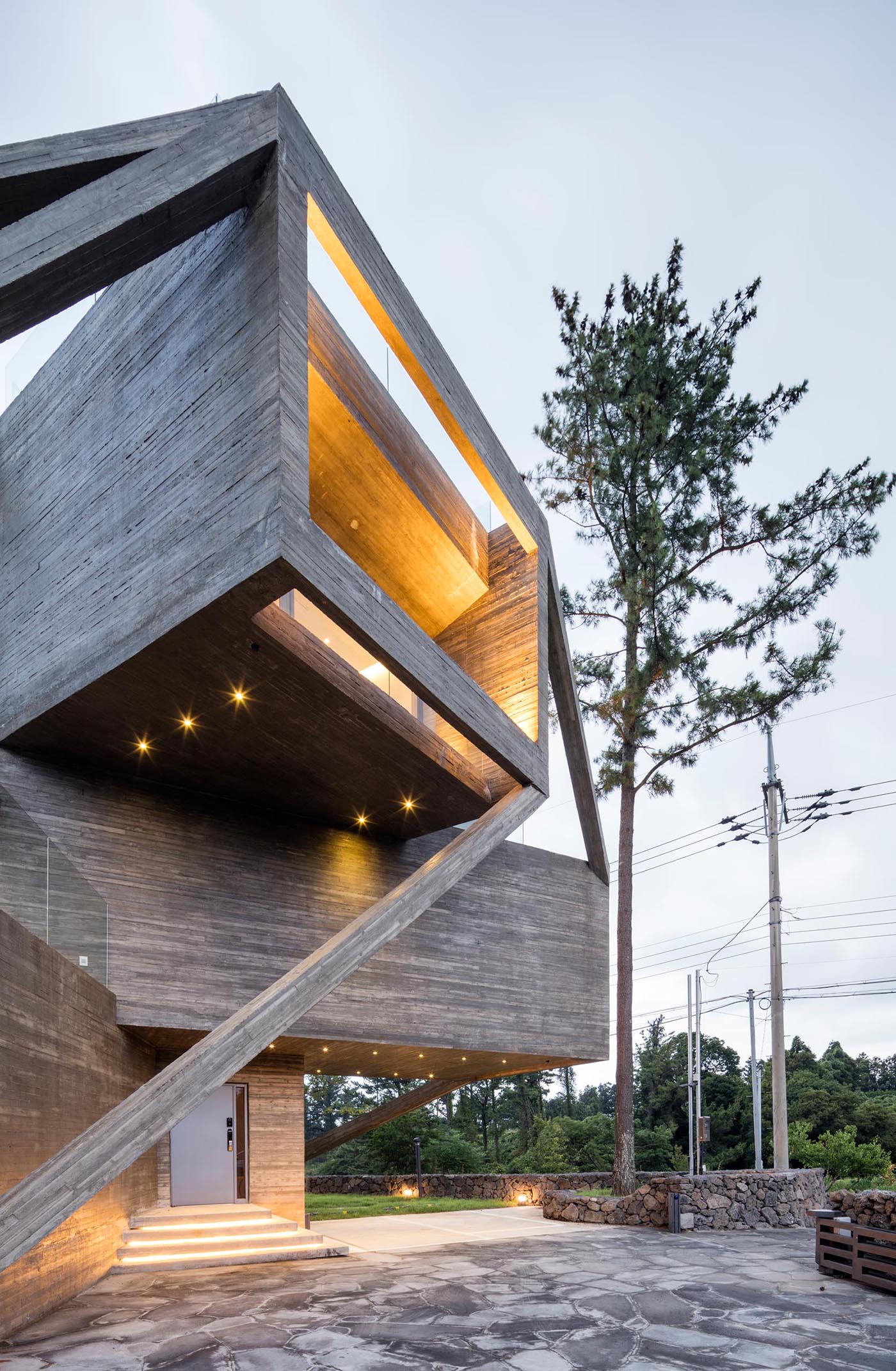 Exterior lighting underneath the various concrete volumes as well as from within the home, bring attention to the various angles and design elements of this modern home.