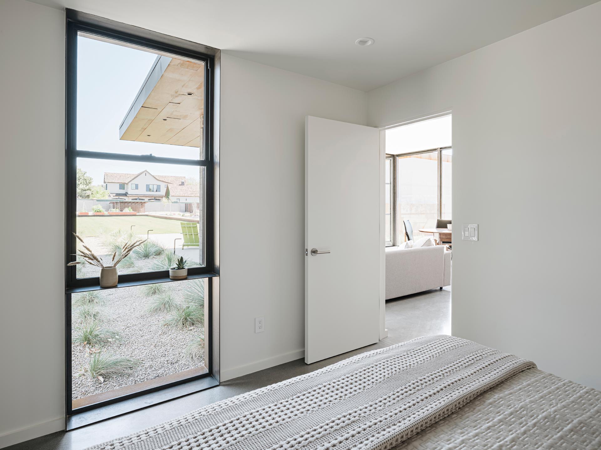 A modern white bedroom with a black window frame.