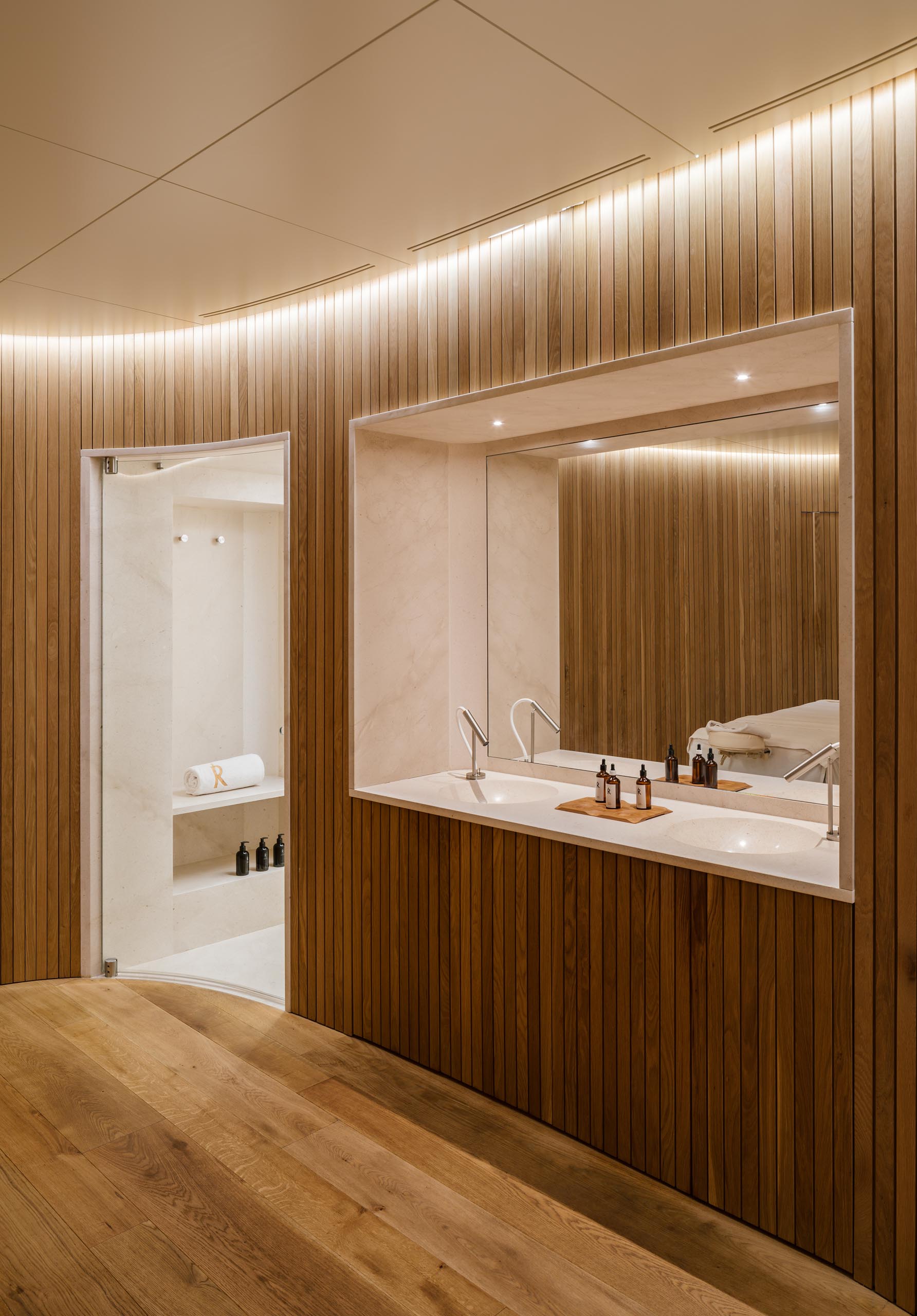 Modern massage rooms with wood slat curved walls and hidden lighting.