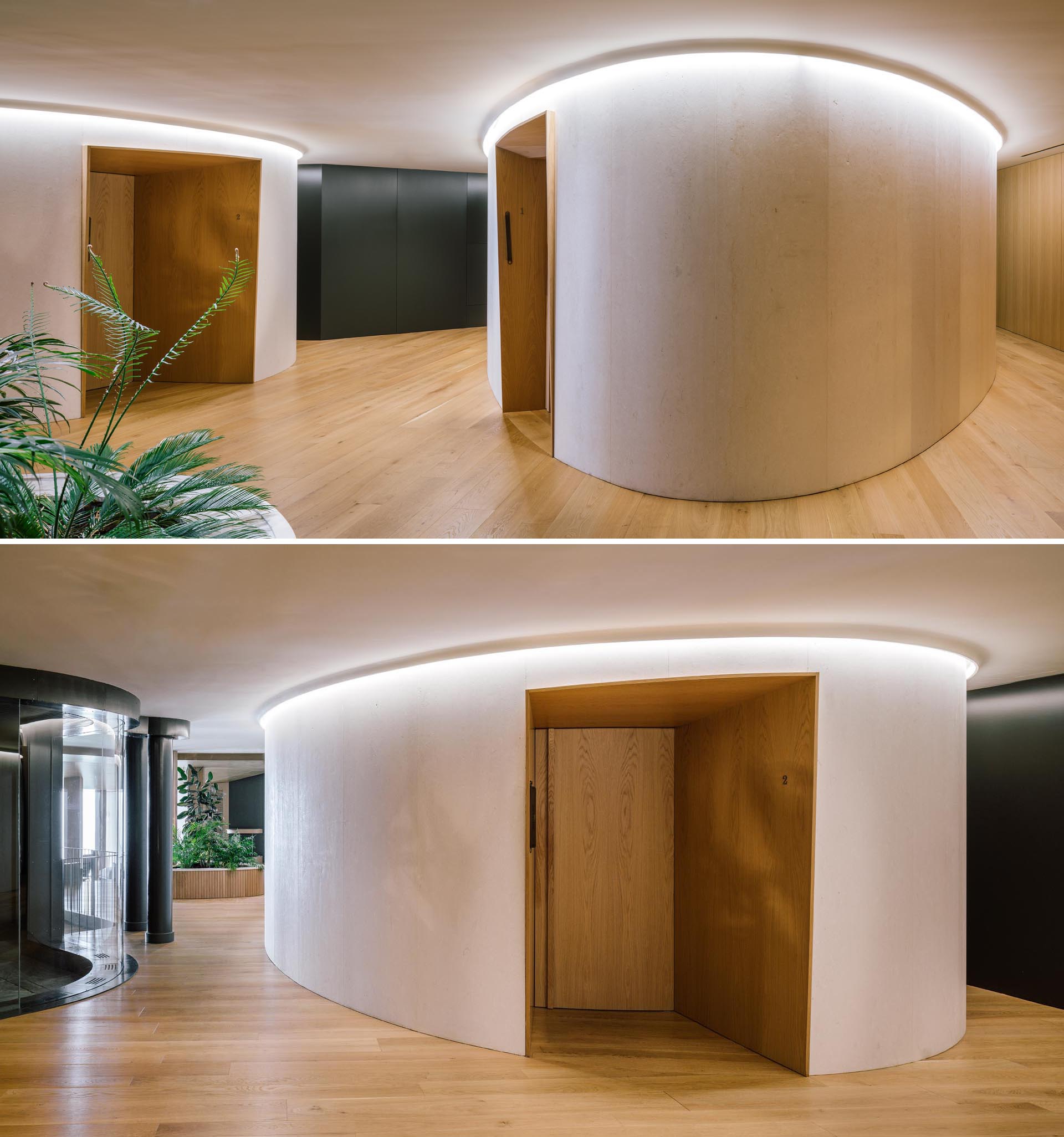 Inside a modern hotel spa, light wood walls are accented by recessed doors, while hidden lighting creates a glow that highlights the curved walls.