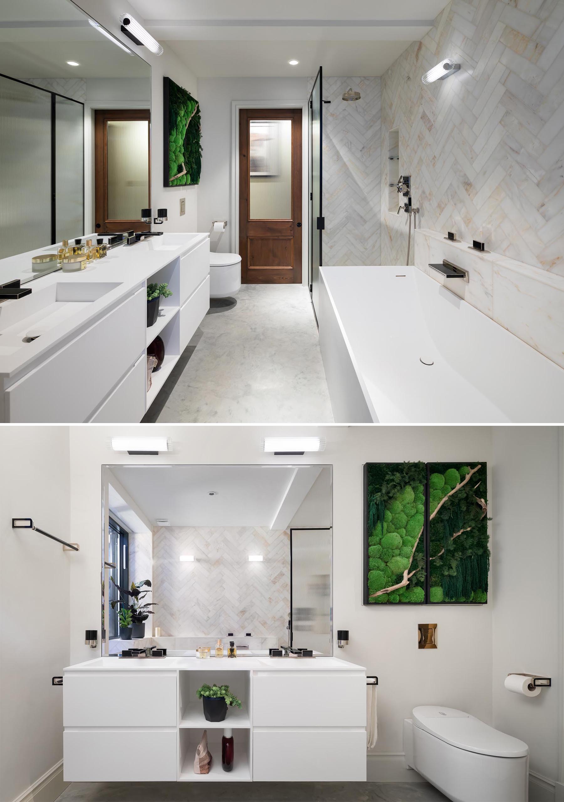 In this modern bathroom, there's a white vanity with dual sinks, a matching bathtub, as well as a walk-in shower and a storage cabinet that hangs above the bathroom and adds a natural design element.