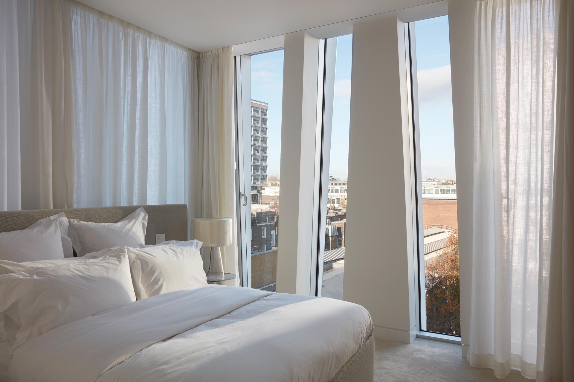 A modern white bedroom with unique triangular window shapes.