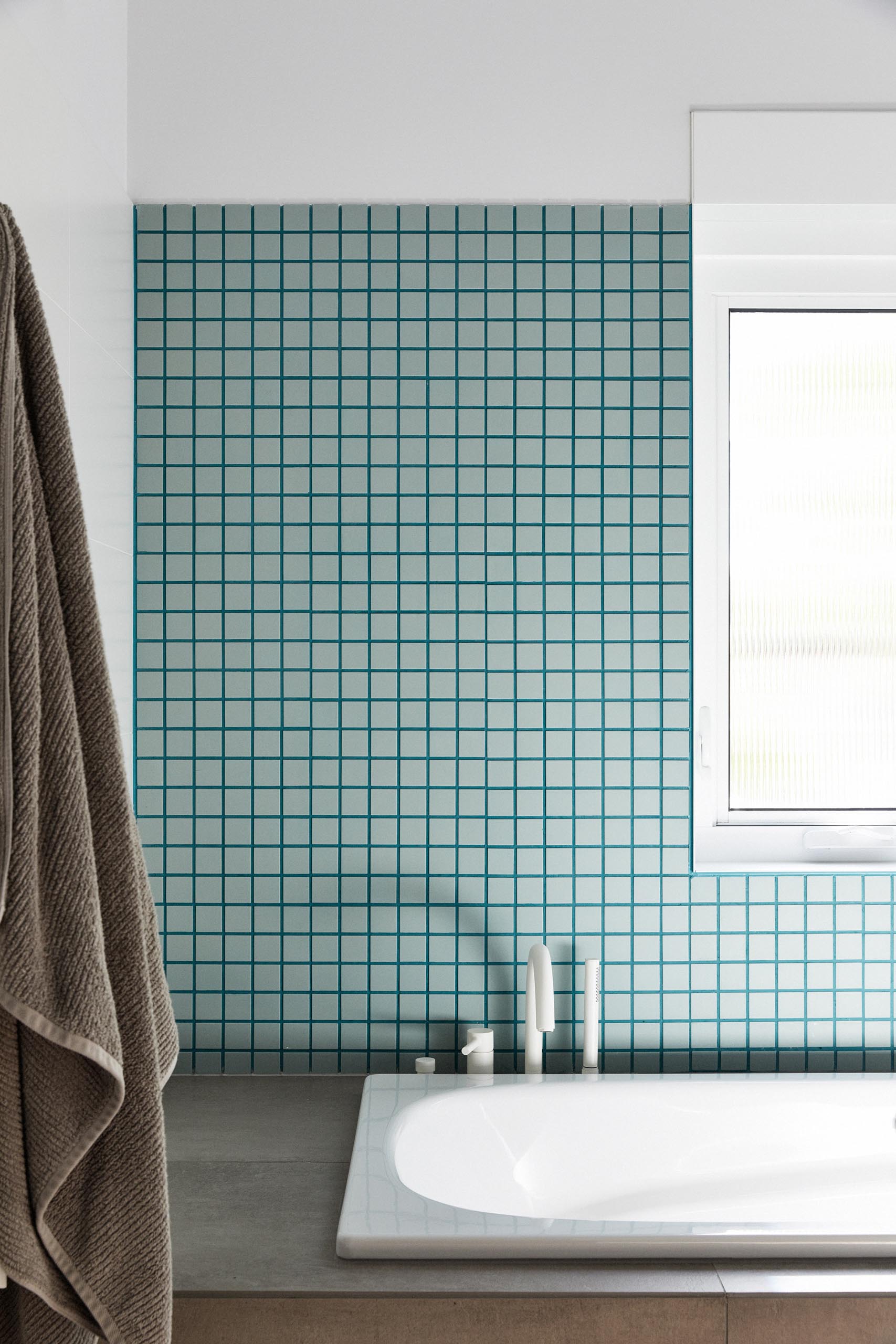 In this modern bathroom, white walls have been paired with soft blue/green tiles and matching grout for a contemporary look.