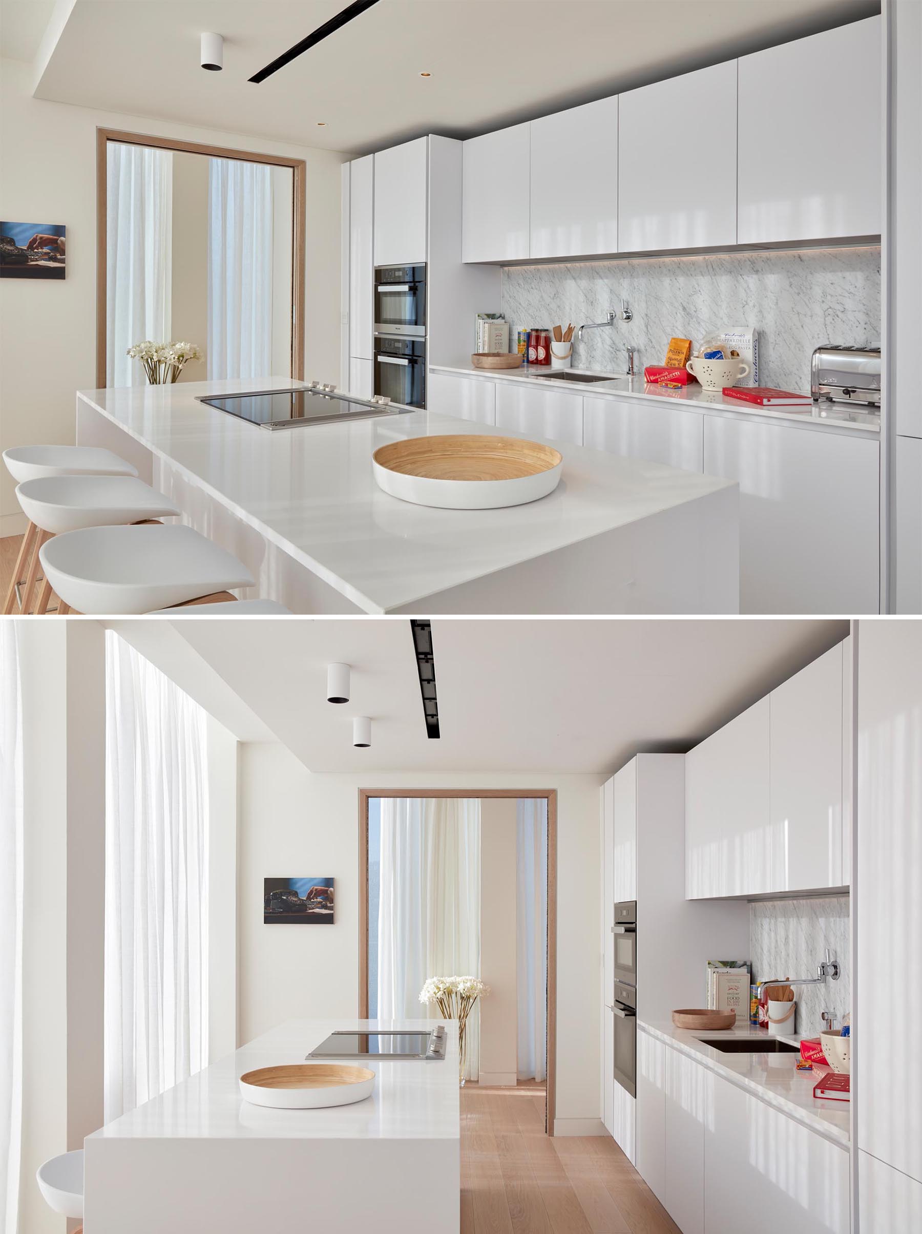 In this modern kitchen, minimalist white cabinets have been used to complement the white countertop and light backsplash.