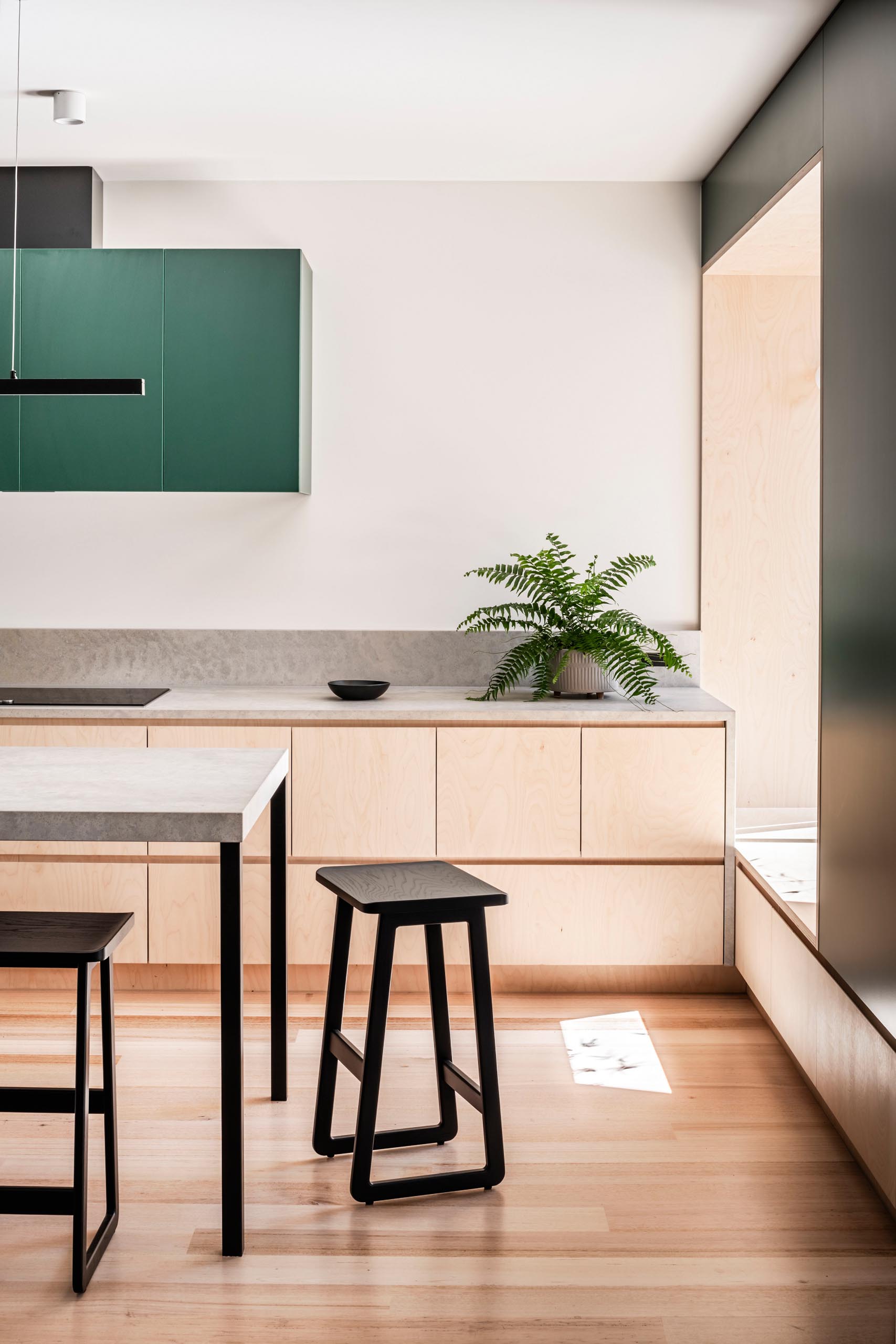 In this modern kitchen, dark green upper cabinets have been wood lower cabinets and concrete countertops.