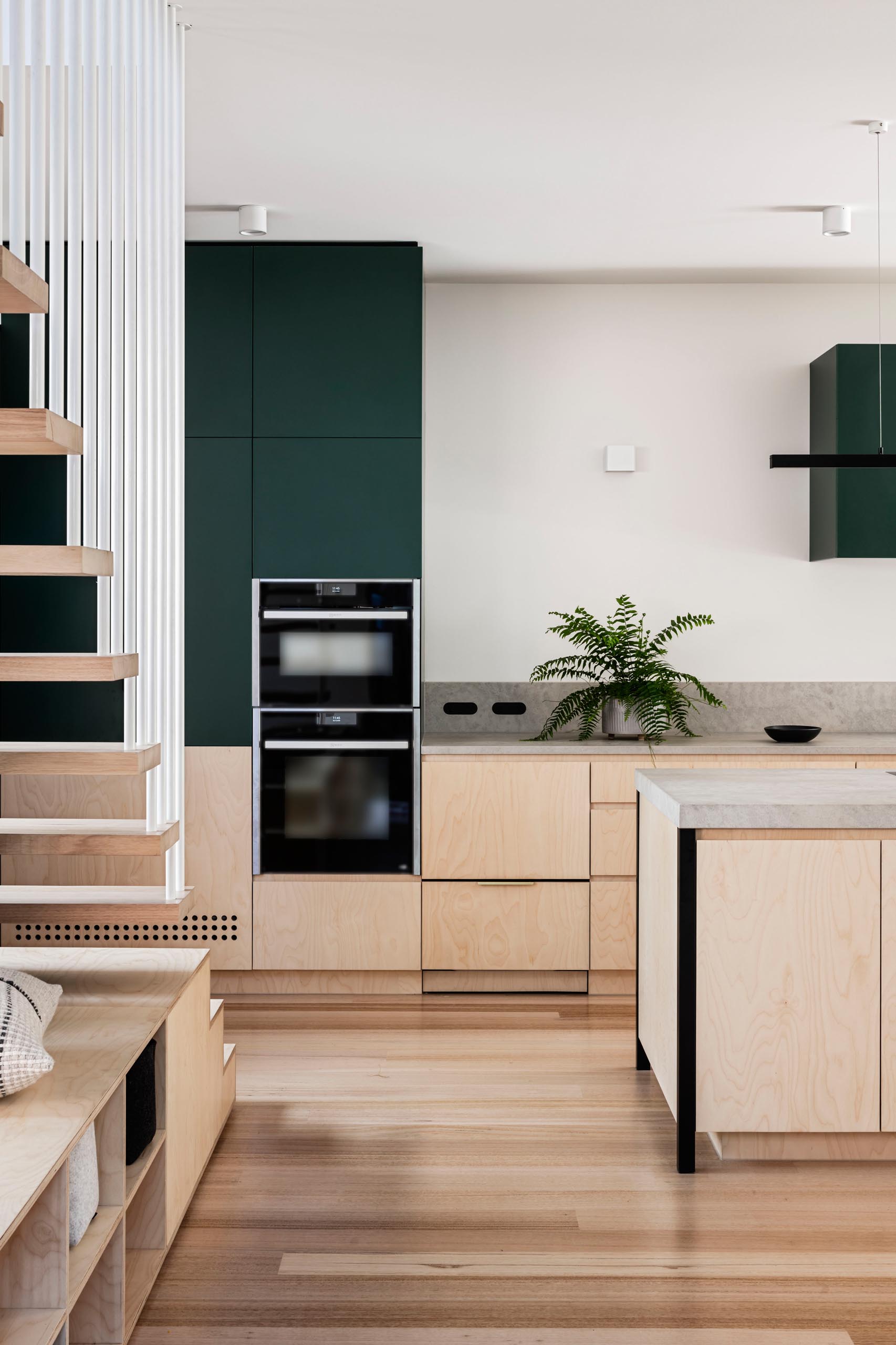 In this modern kitchen, dark green upper cabinets have been wood lower cabinets and concrete countertops.