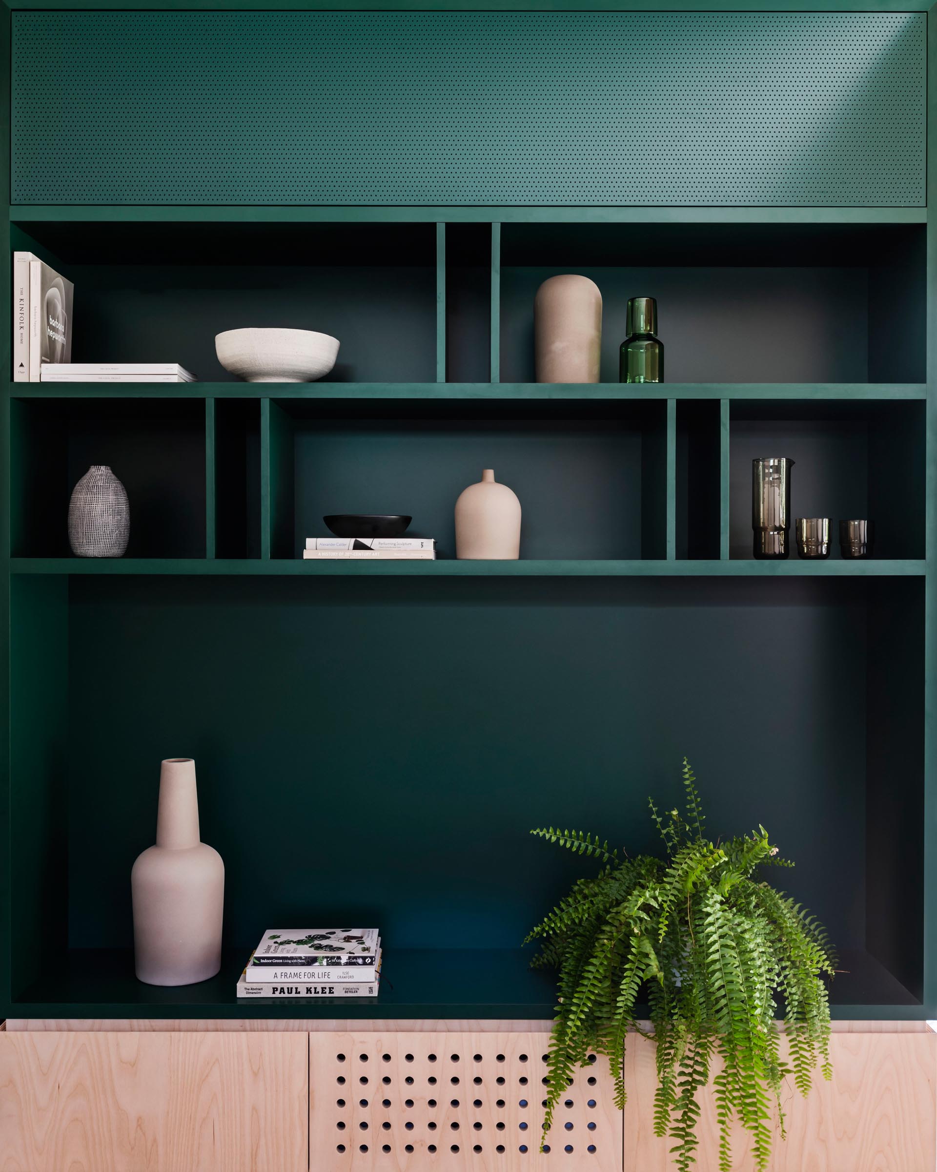 Modern dark green shelving is paired with wood cabinets.