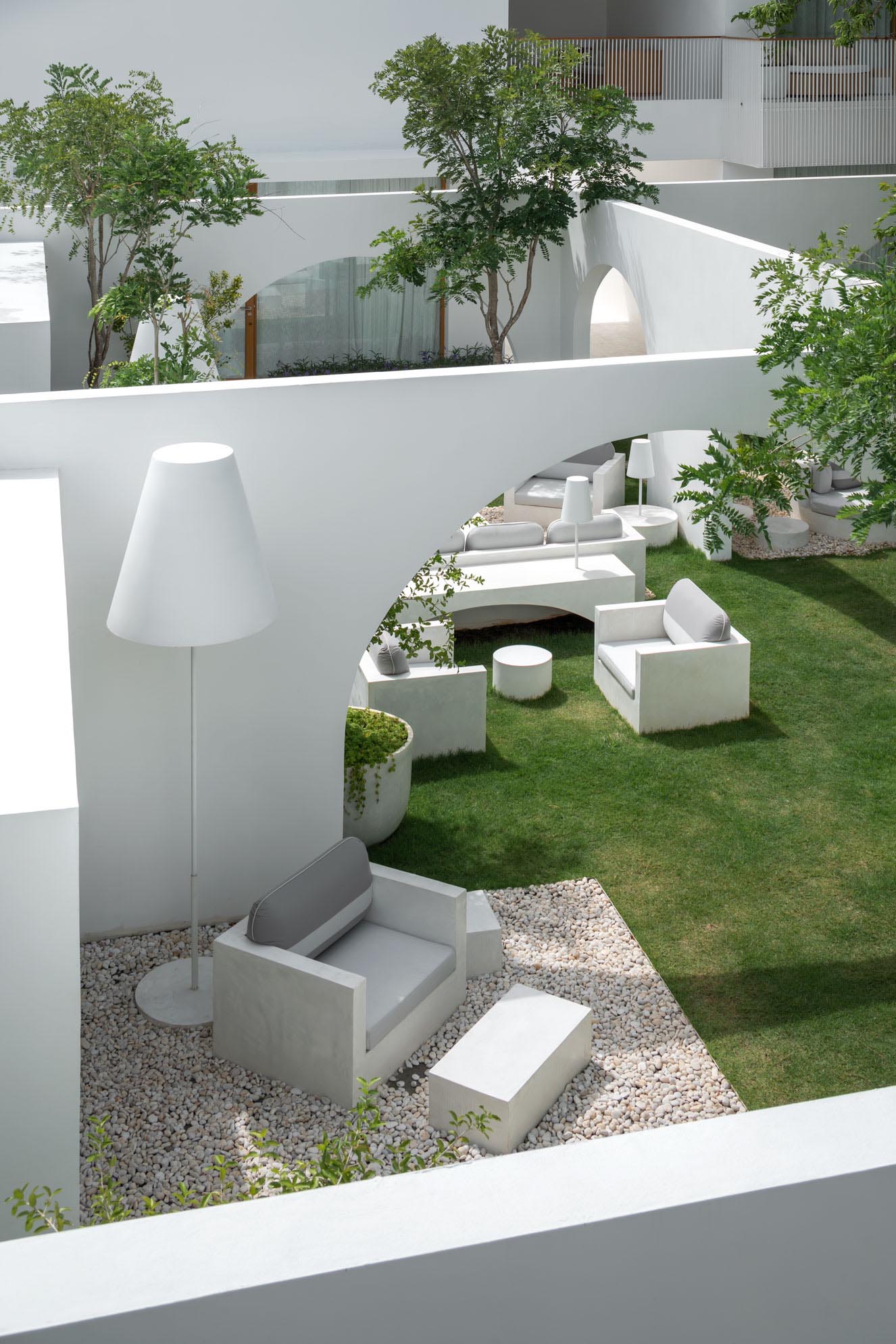 An outdoor sitting room with pebbles and oversized lighting.