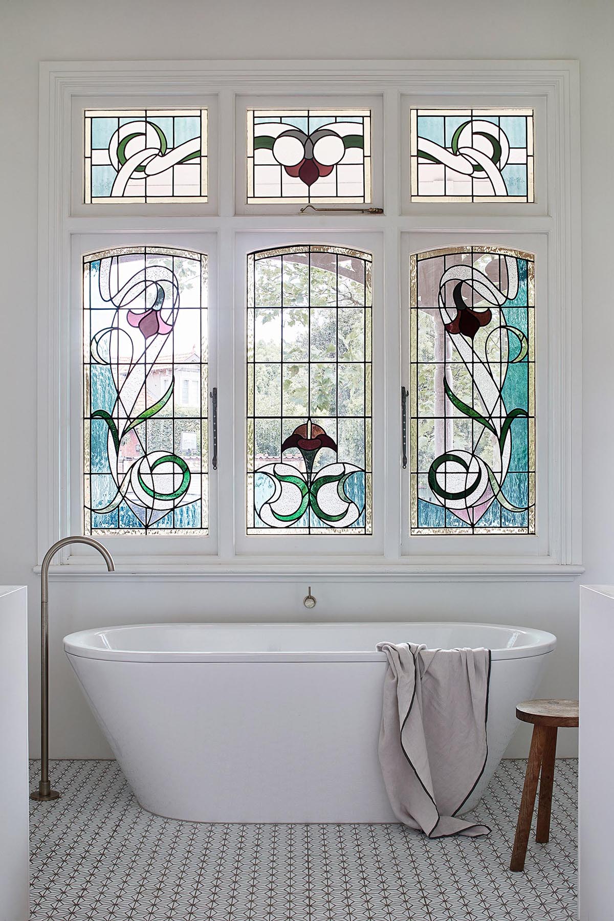 A bathroom with a stained glass window and a modern freestanding bathtub.