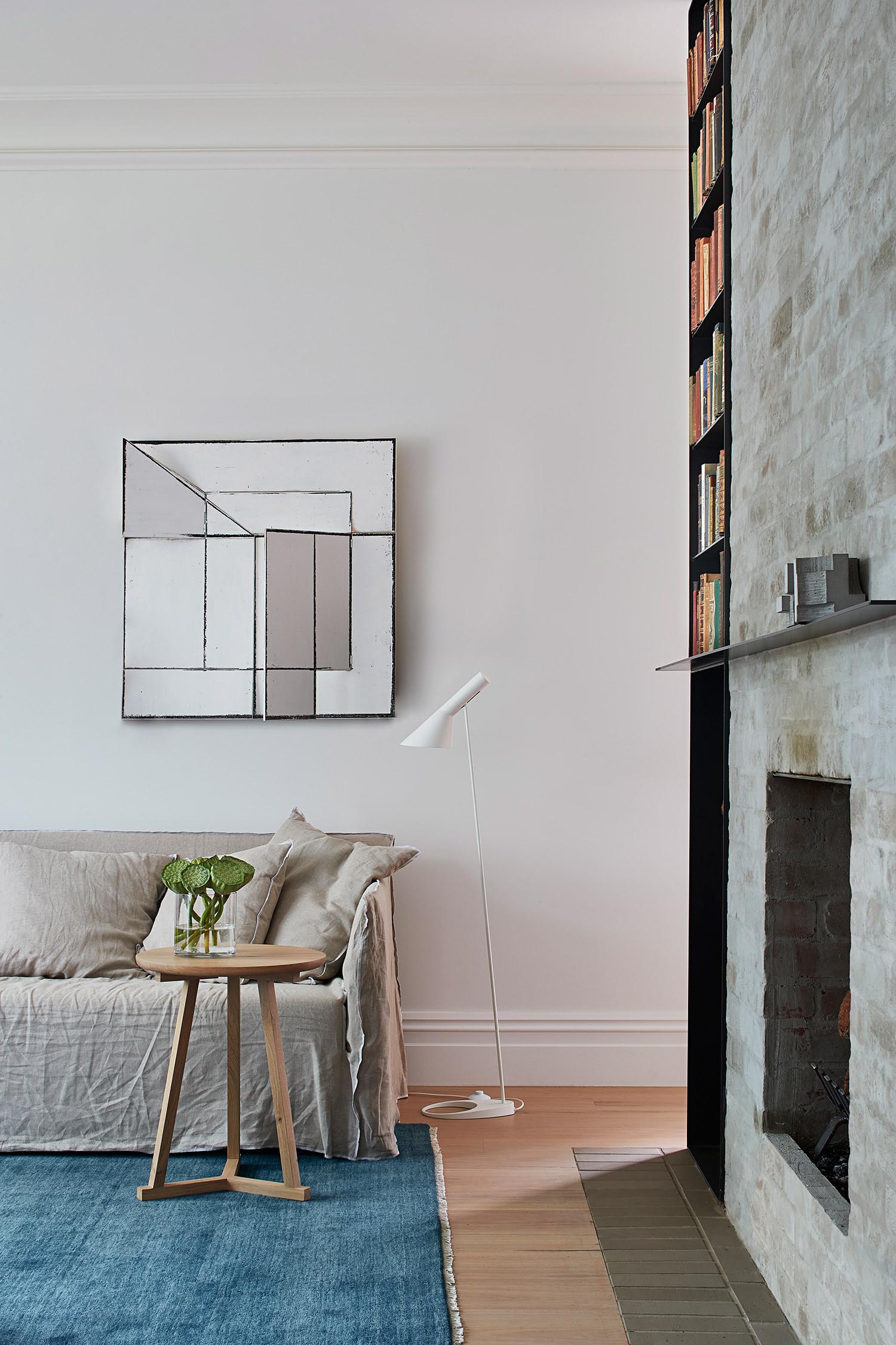 A remodeled living room with a brick fireplace that includes firewood storage and a bookshelf.