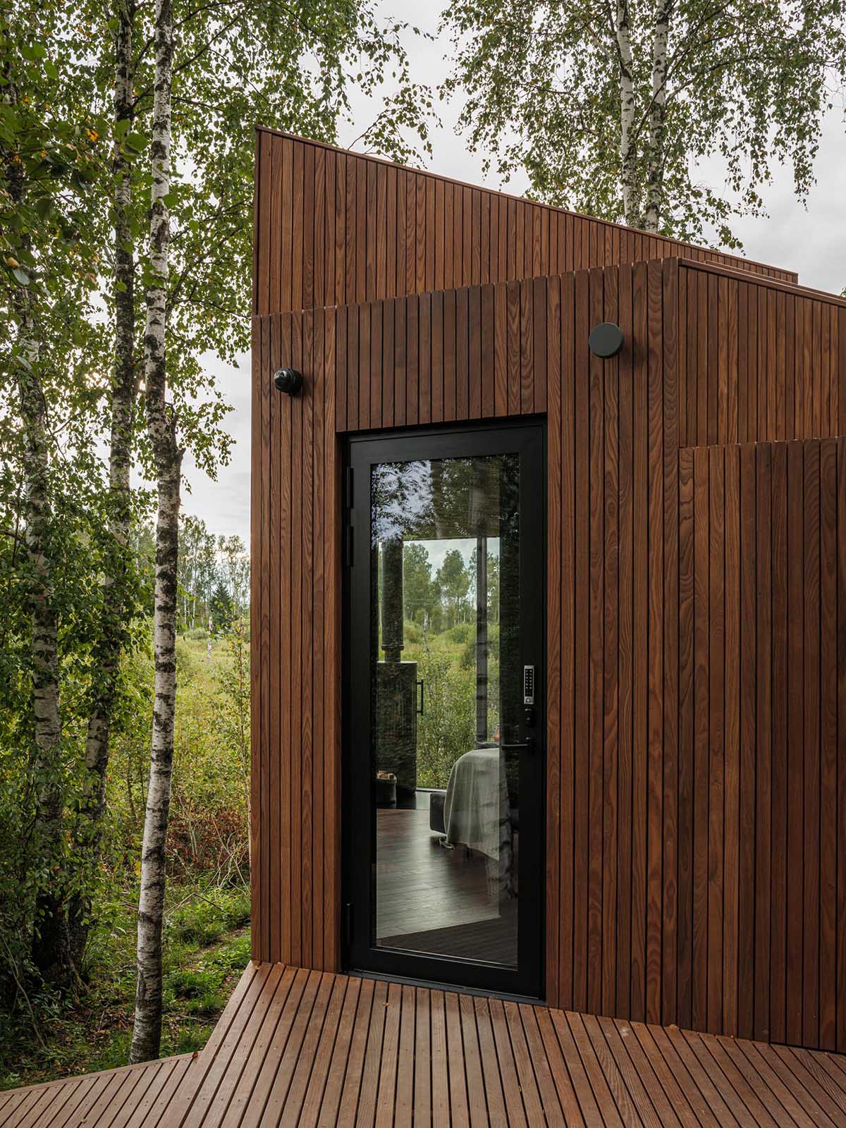 A black-framed glass door provides a glimpse of the interior and views beyond.