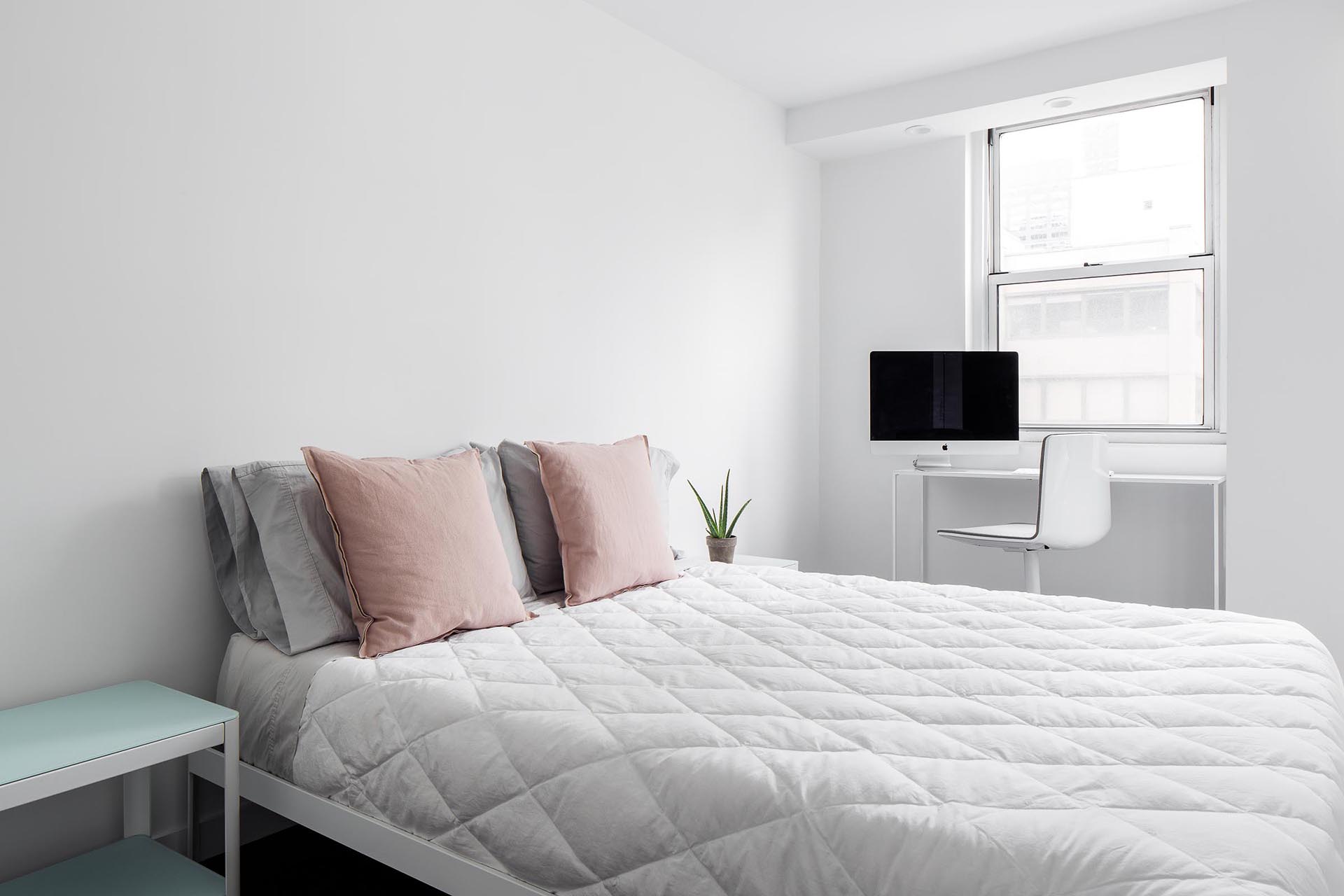 A minimally furnished bedroom with a desk by the window.