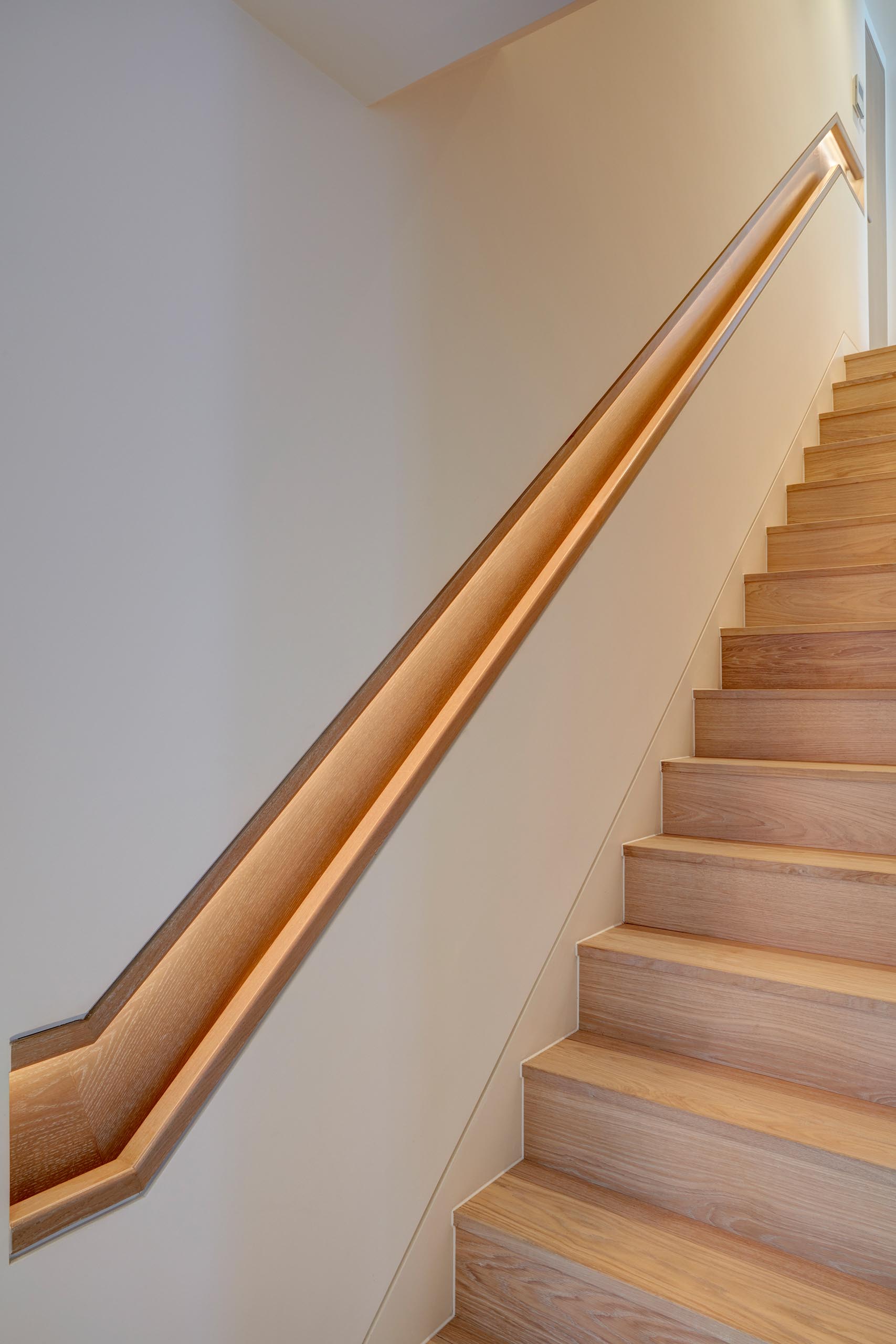Modern wood stairs and a matching wood handrail with hidden lighting.