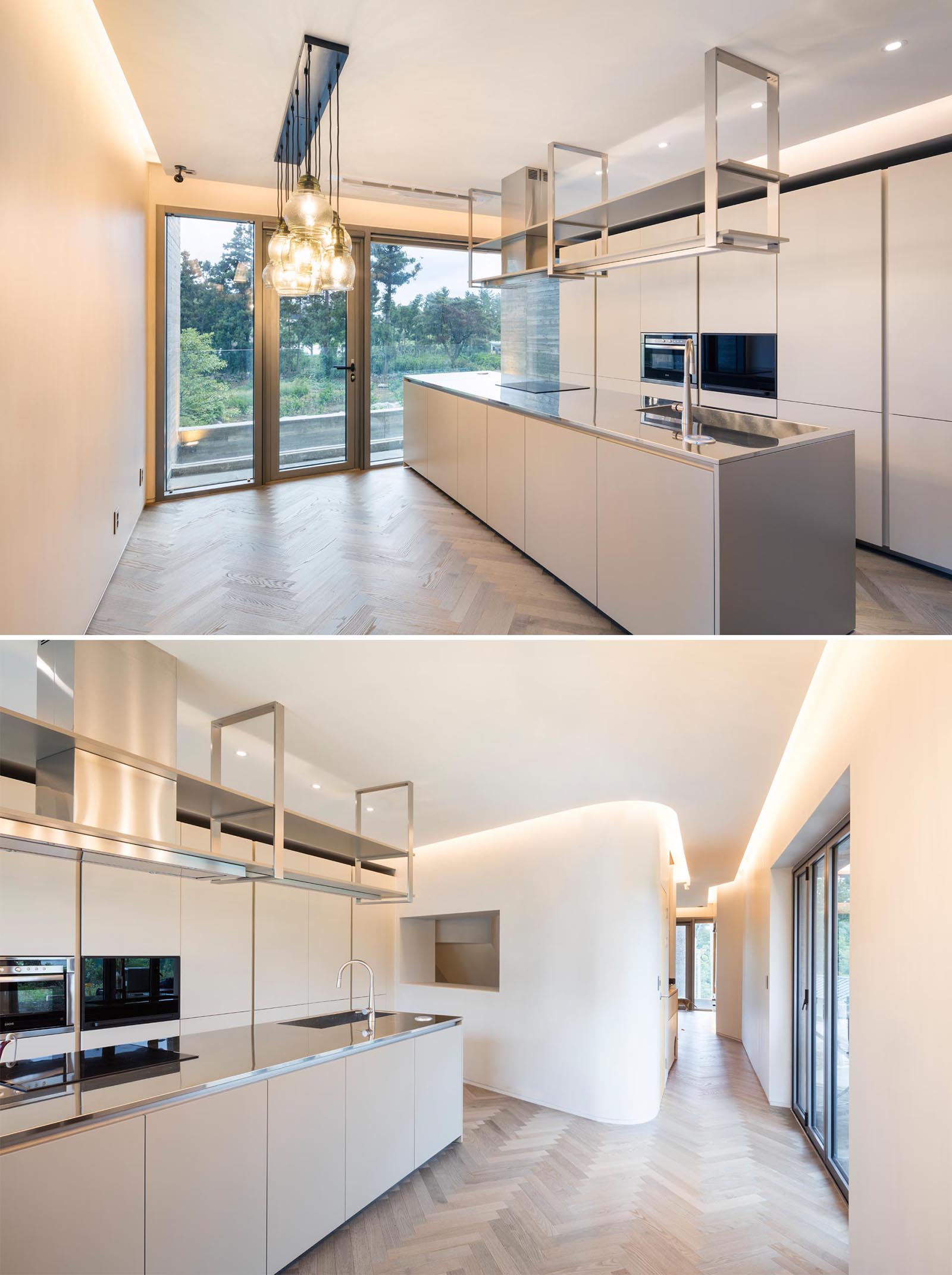 A modern kitchen with white walls and cabinets, wood flooring, and hidden lighting. 