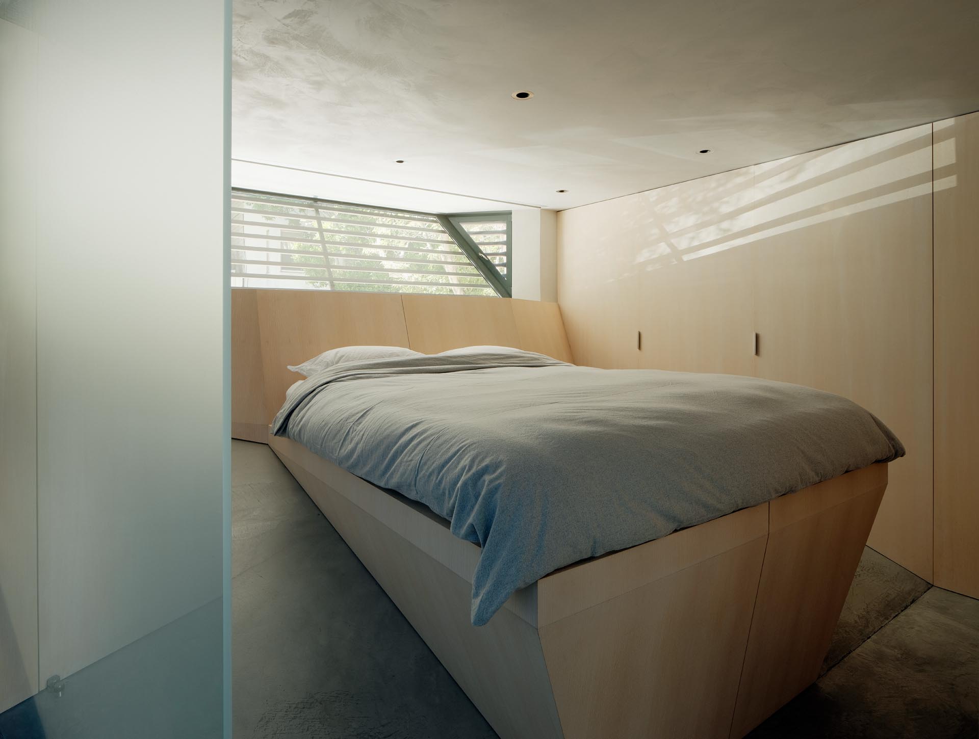 A modern bedroom with a custom designed angled wood bed frame that allows the bed to be level.