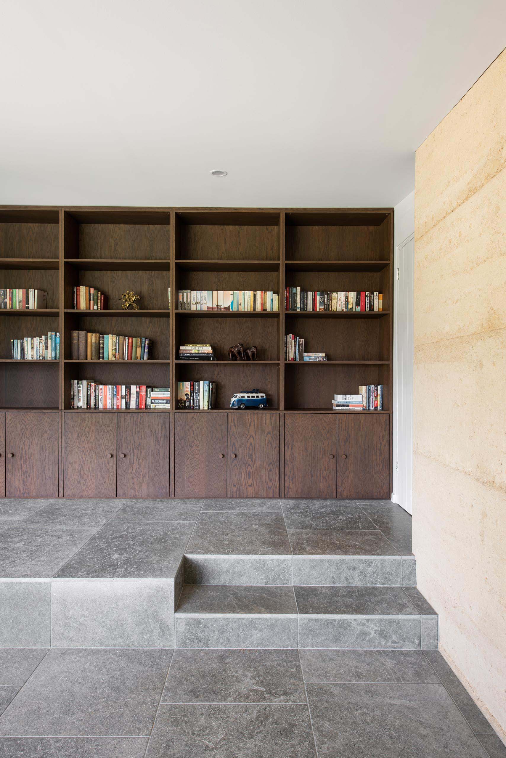 A large dark wood custom bookshelf that includes storage cabinets below.