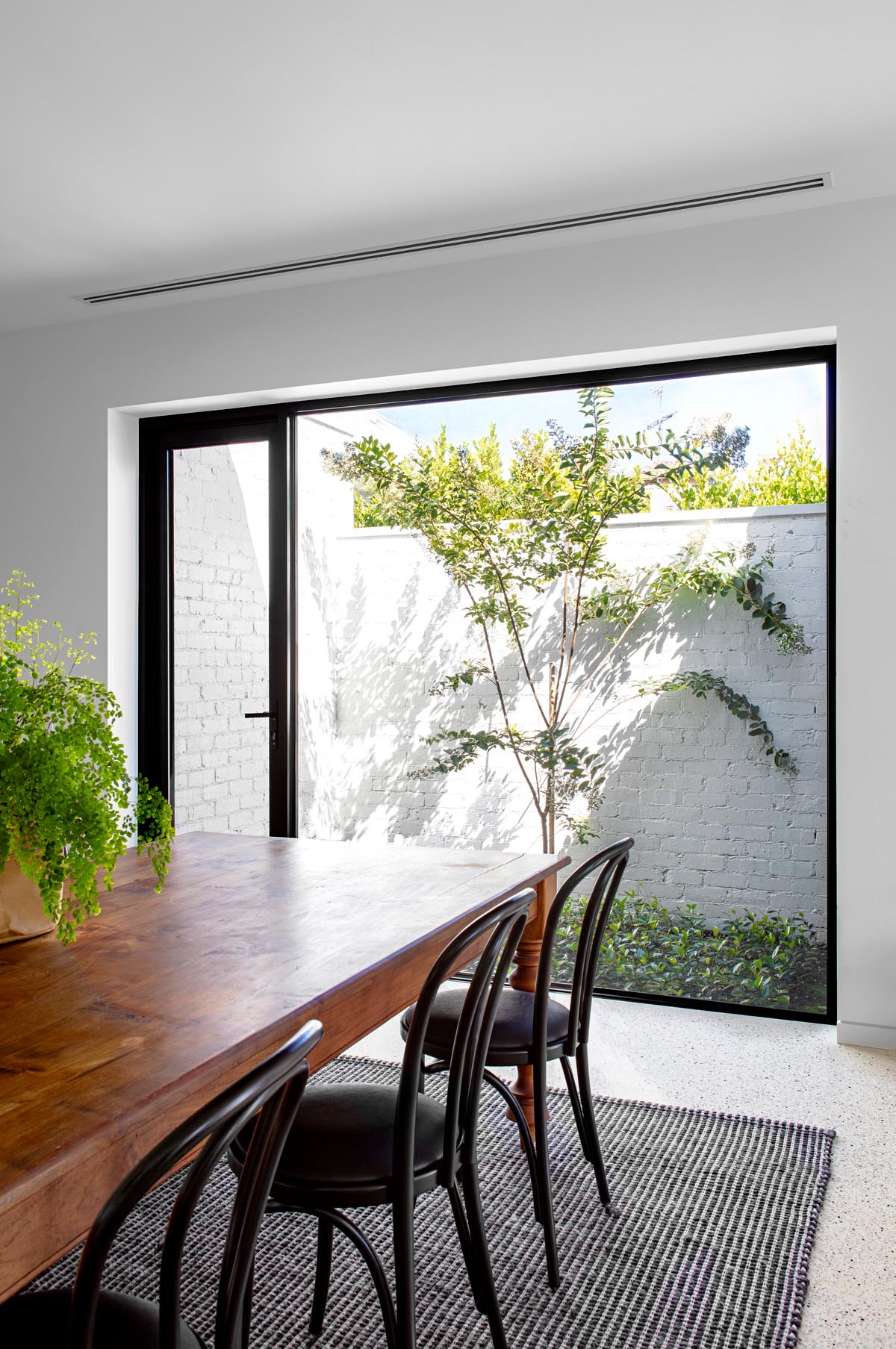 A large picture window by this dining area perfectly frames the tree outside.