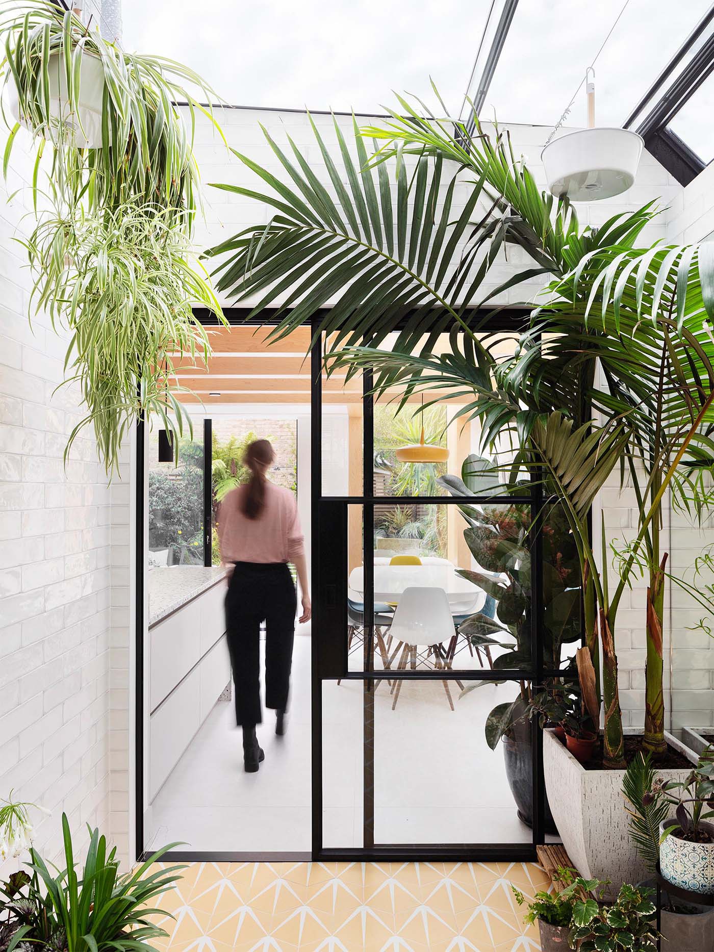 An interior garden room with automated skylights, Ochre floor tiles, an irrigation system, and plenty of plants.