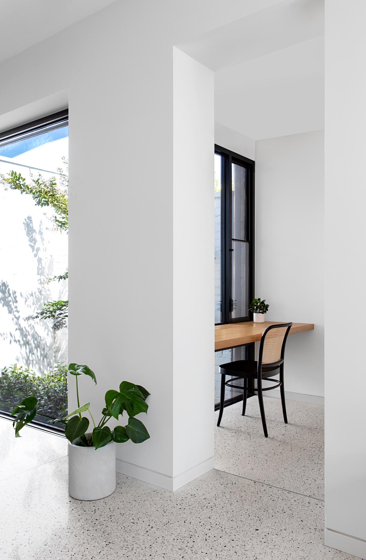 A modern home office with a solid oak wood desk that takes advantage of the window views.