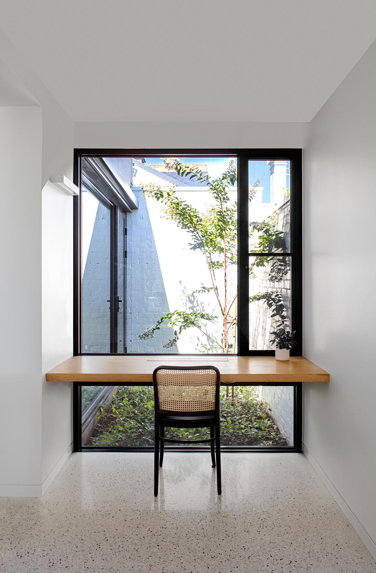 A modern home office with a solid oak wood desk that takes advantage of the window views.