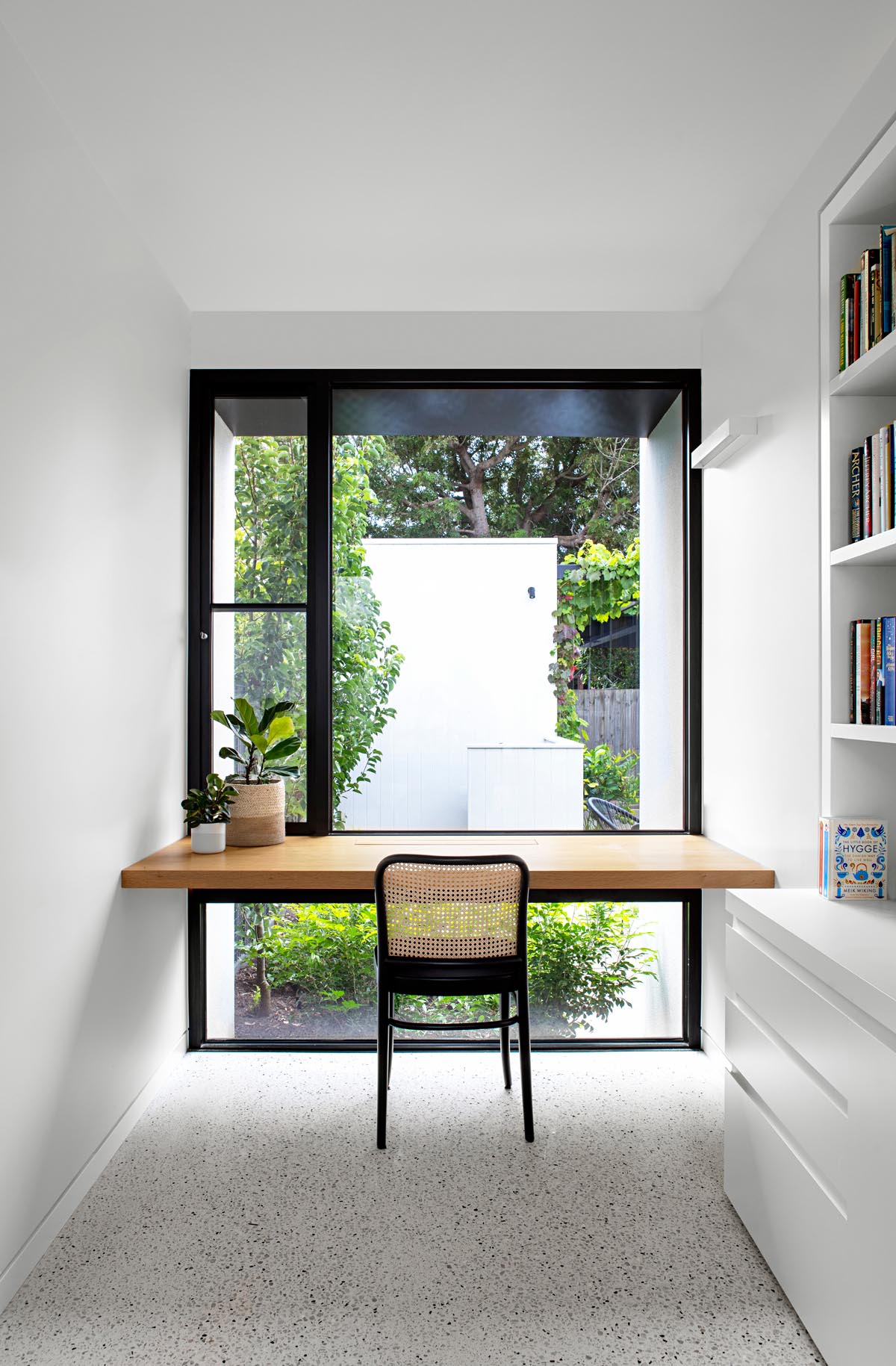 A modern home office with a solid oak wood desk that takes advantage of the window views.