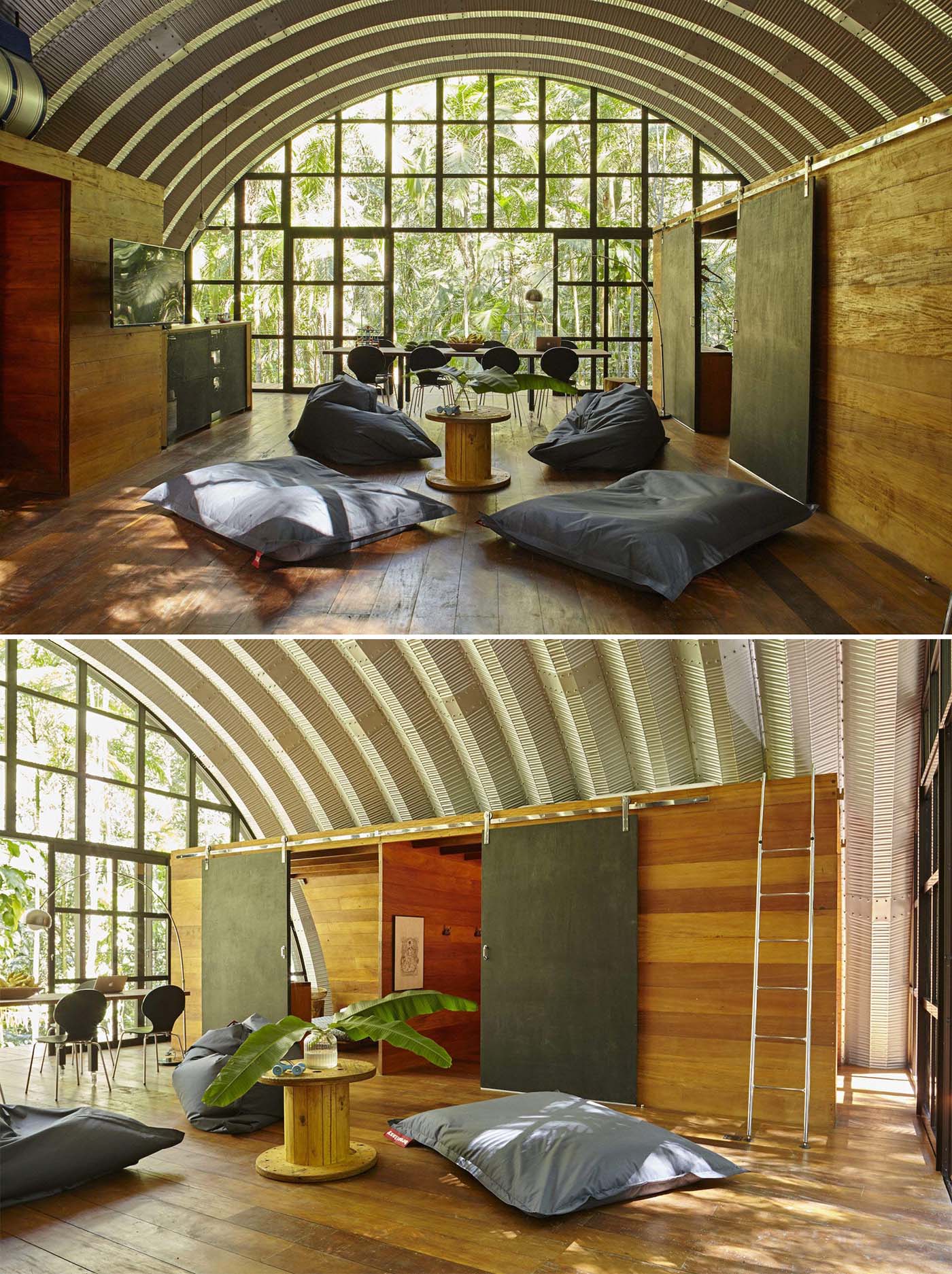 A modern home with an arched metal roof has an open floor plan, and a full wall of windows.