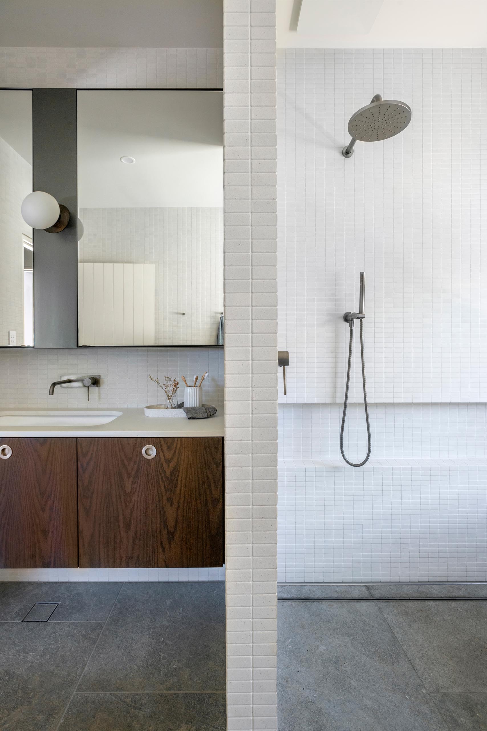 Phòng tắm hiện đại với bàn trang điểm bằng gỗ tối màu kết hợp với sàn tối màu và tường sáng màu.