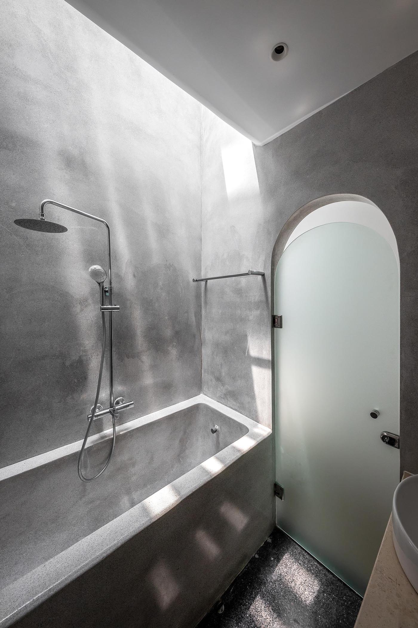 A modern grey bathroom with a frosted door, as well as a built-in bathtub.