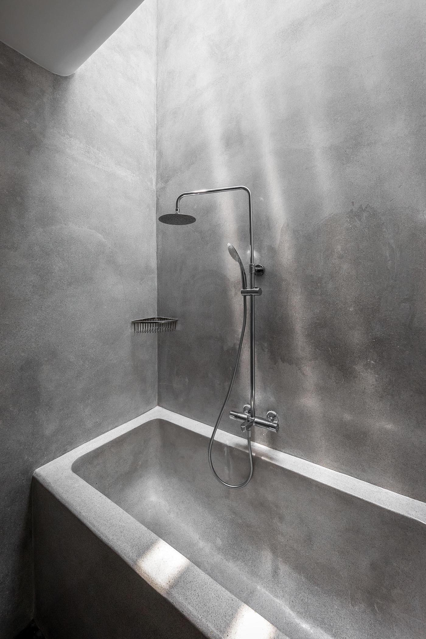 A modern grey bathroom with a frosted door, as well as a built-in bathtub.