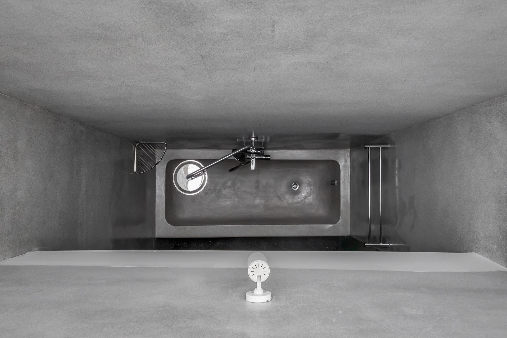 A modern grey bathroom with a frosted door, as well as a built-in bathtub.