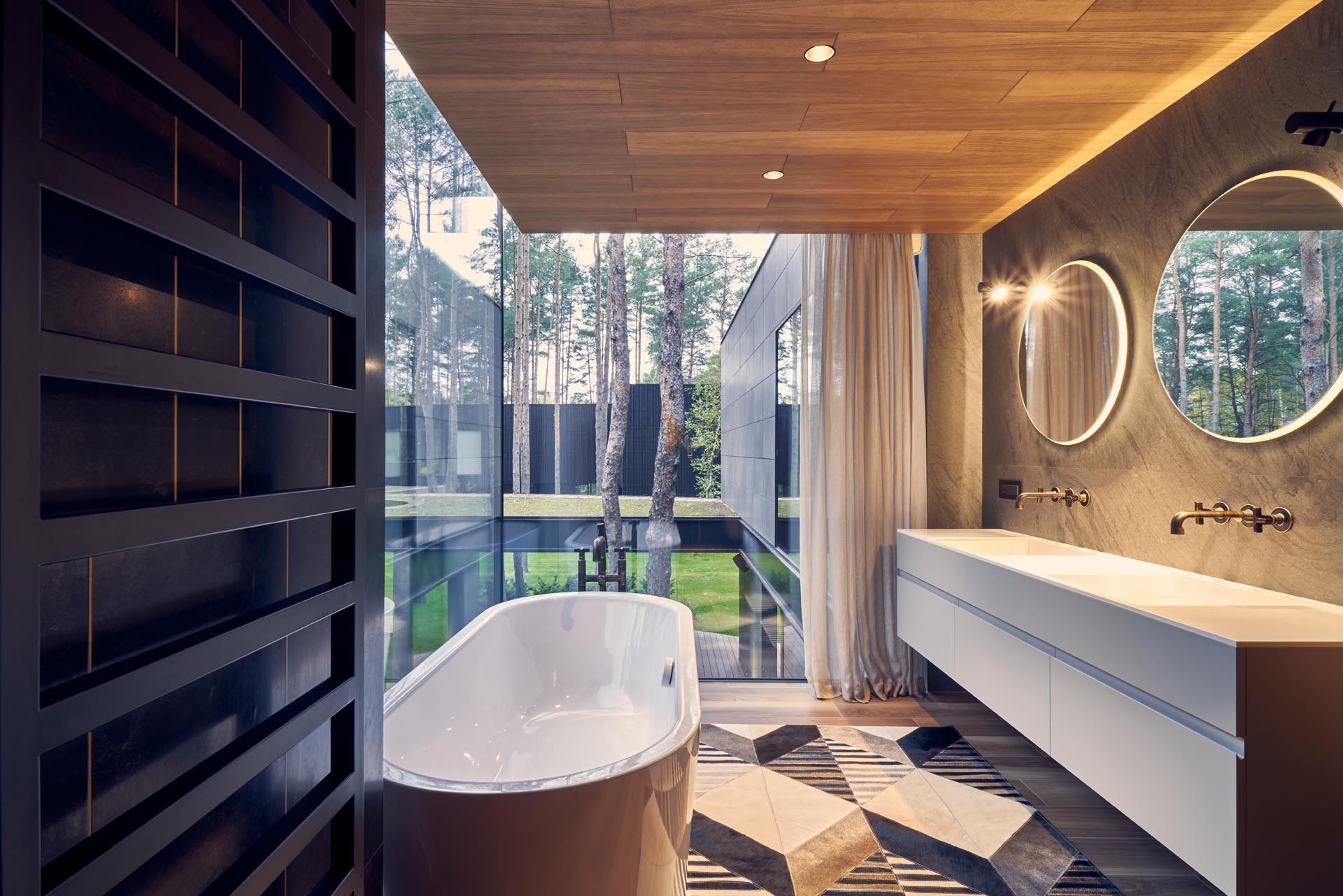 A modern bathroom with corner windows, round mirrors, a wood ceiling, and a floating white vanity with double sinks.