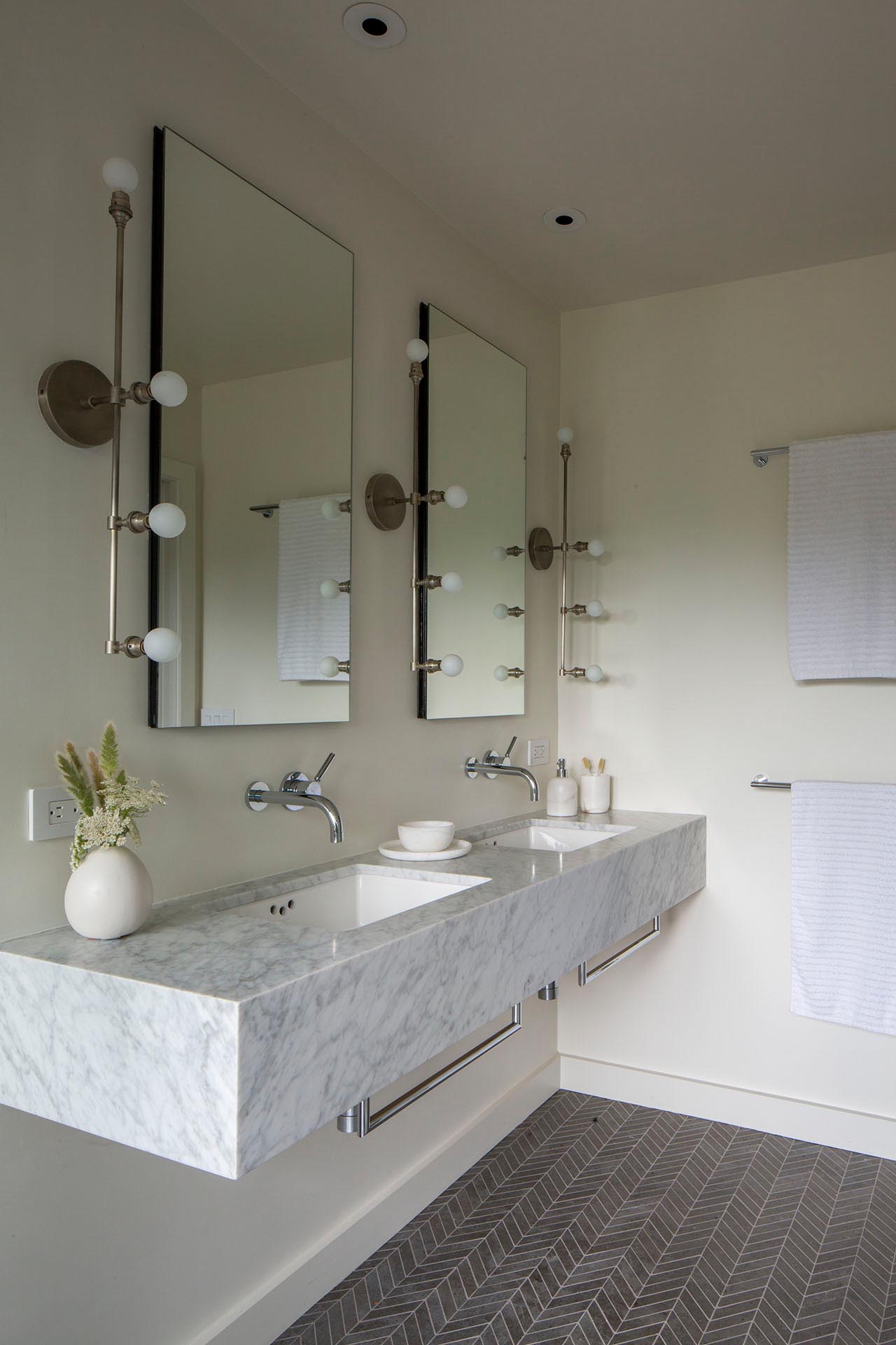 A modern bathroom with a floating vanity and patterned tile flooring.