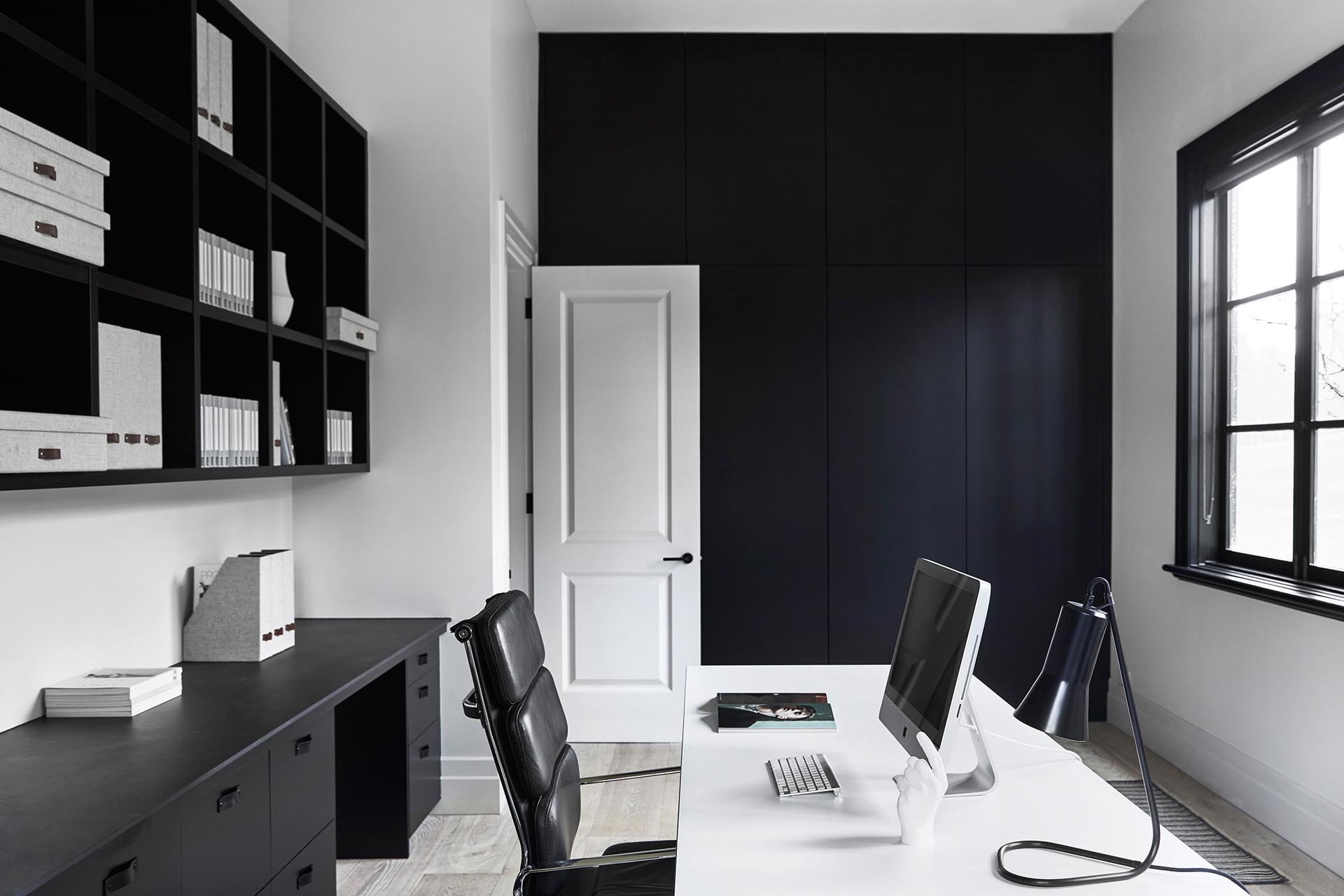 This modern home office has been kept minimally furnished with the black joinery complementing the black window frames.