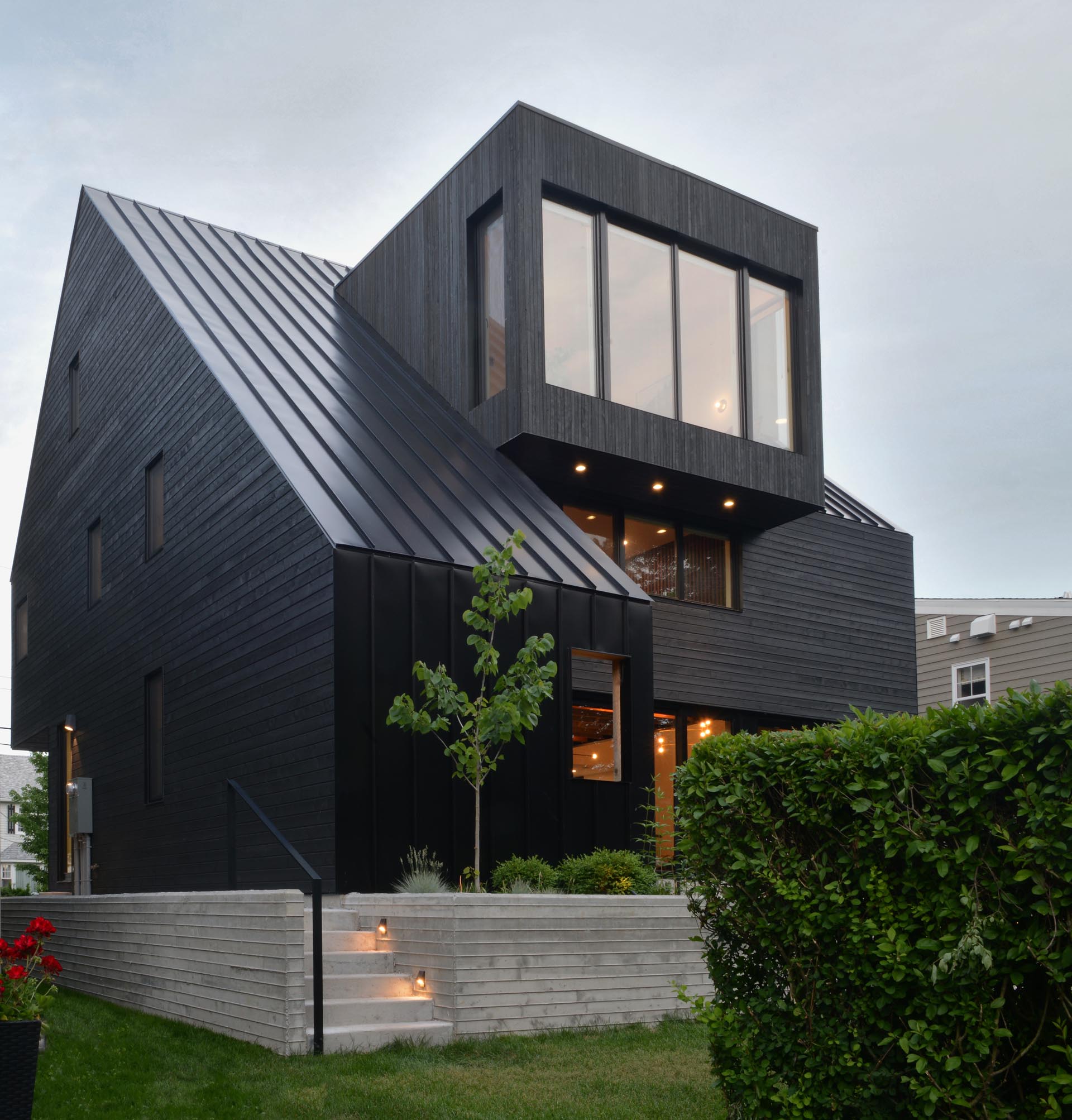 A modern black house with wood siding and a standing seam metal roof.