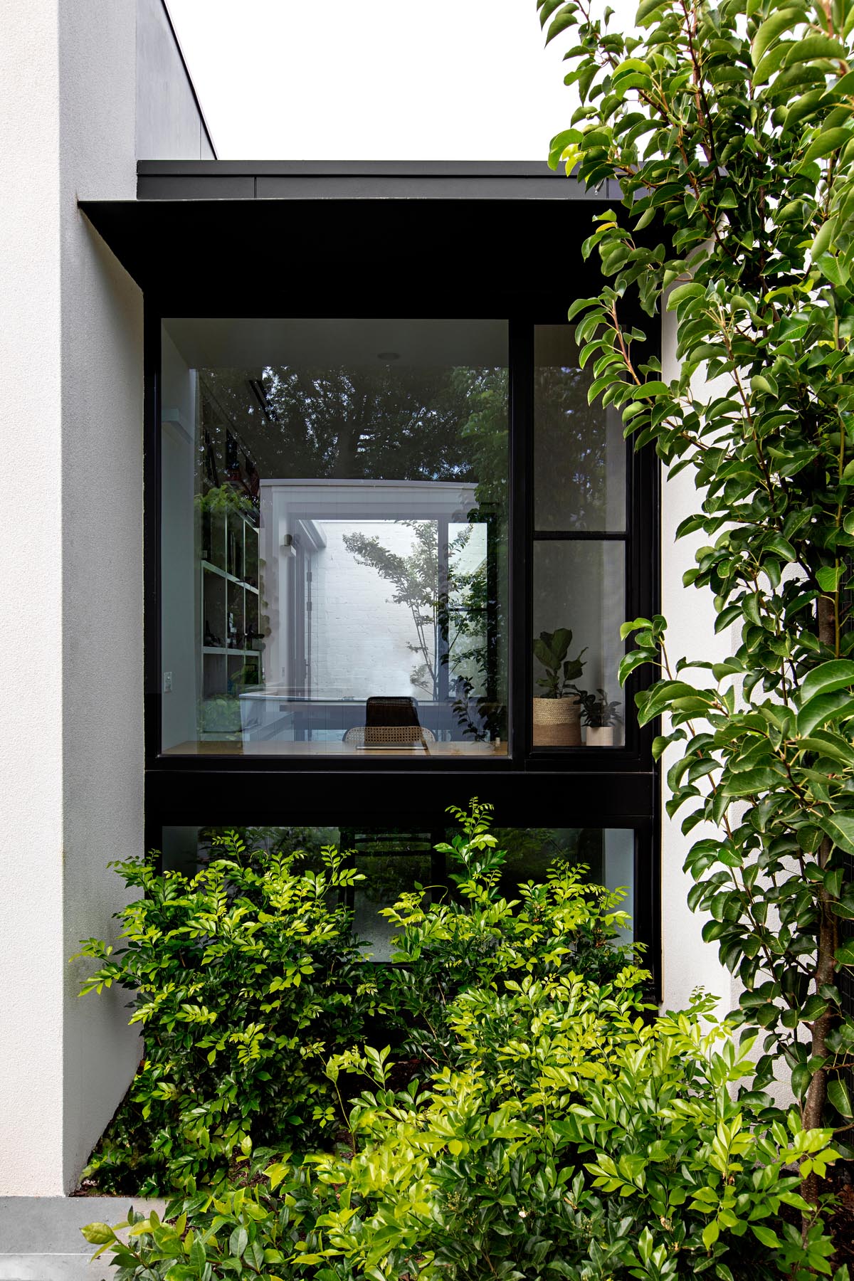 A home office with black window frames that has views of the garden.