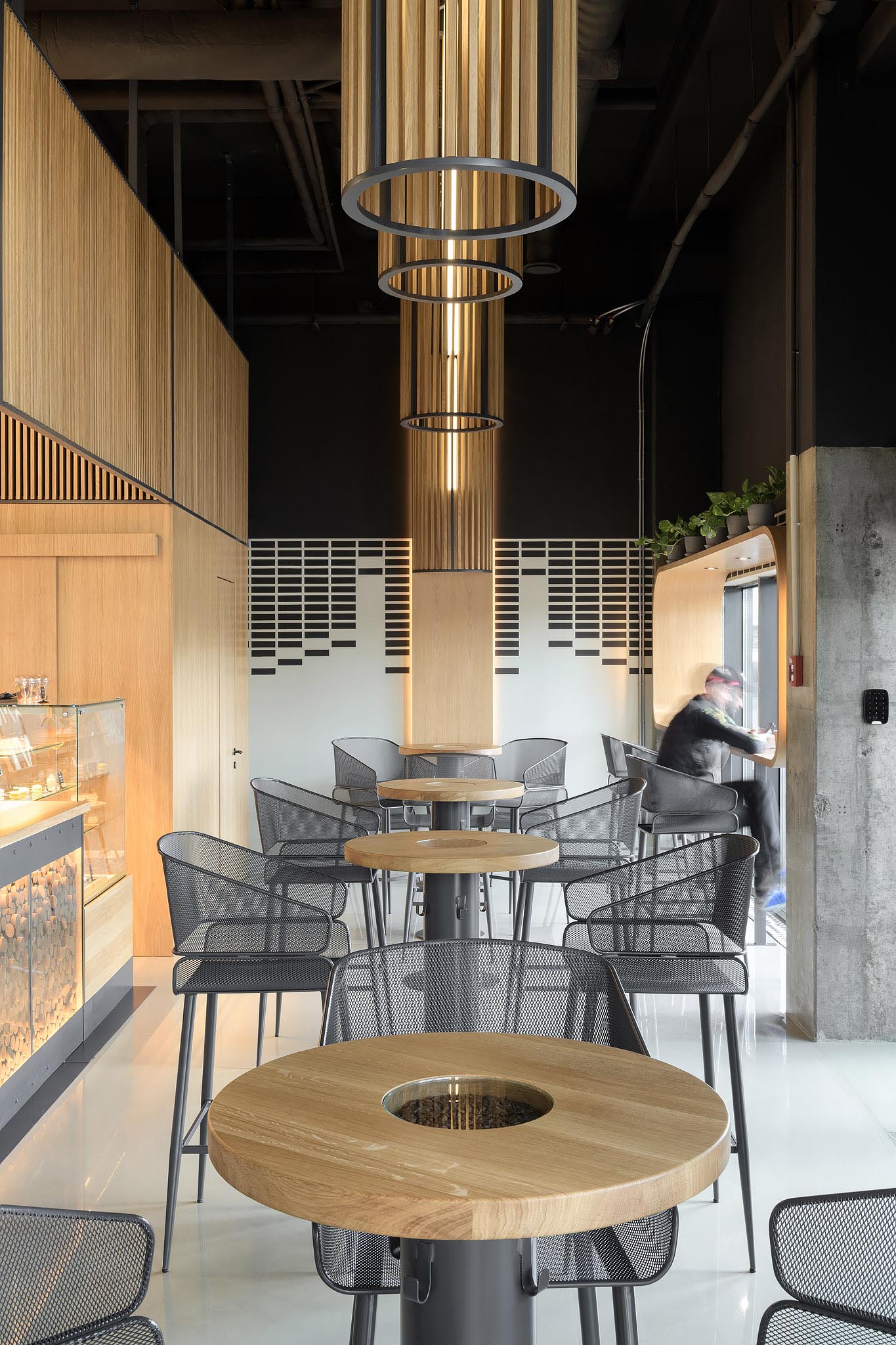 A series of tall bar tables placed under the ceiling lights separates the service area from the window counter. The cores in the center of the table tops are where real coffee beans are poured.