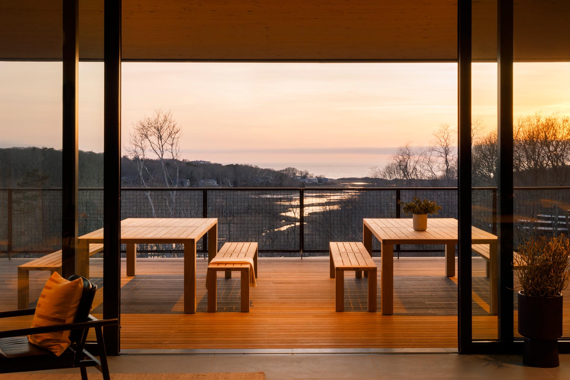 Large sliding glass doors open to a covered balcony that has outdoor dining with views of the water and surrounding landscape.