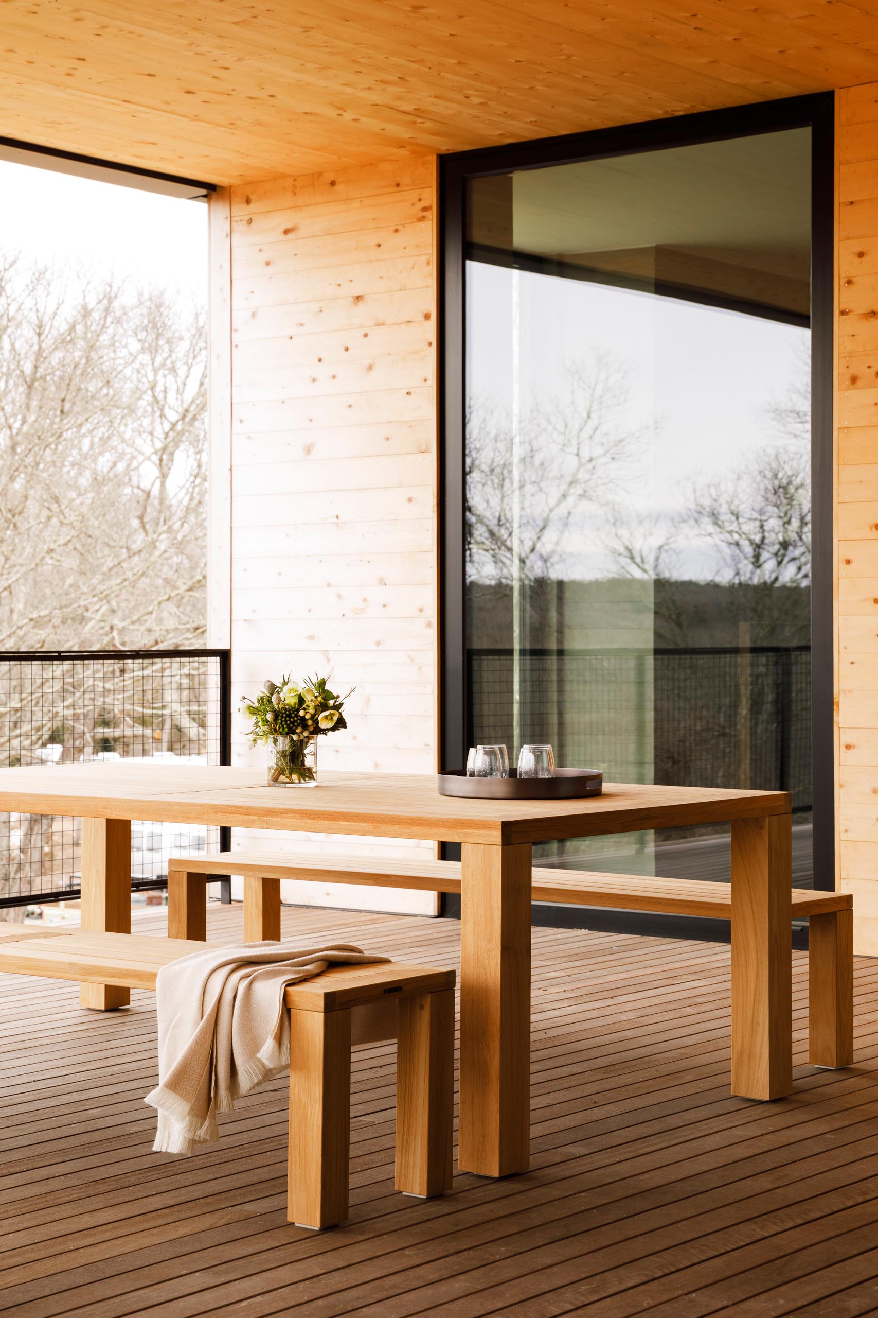 Large sliding glass doors open to a covered balcony that has outdoor dining with views of the water and surrounding landscape.