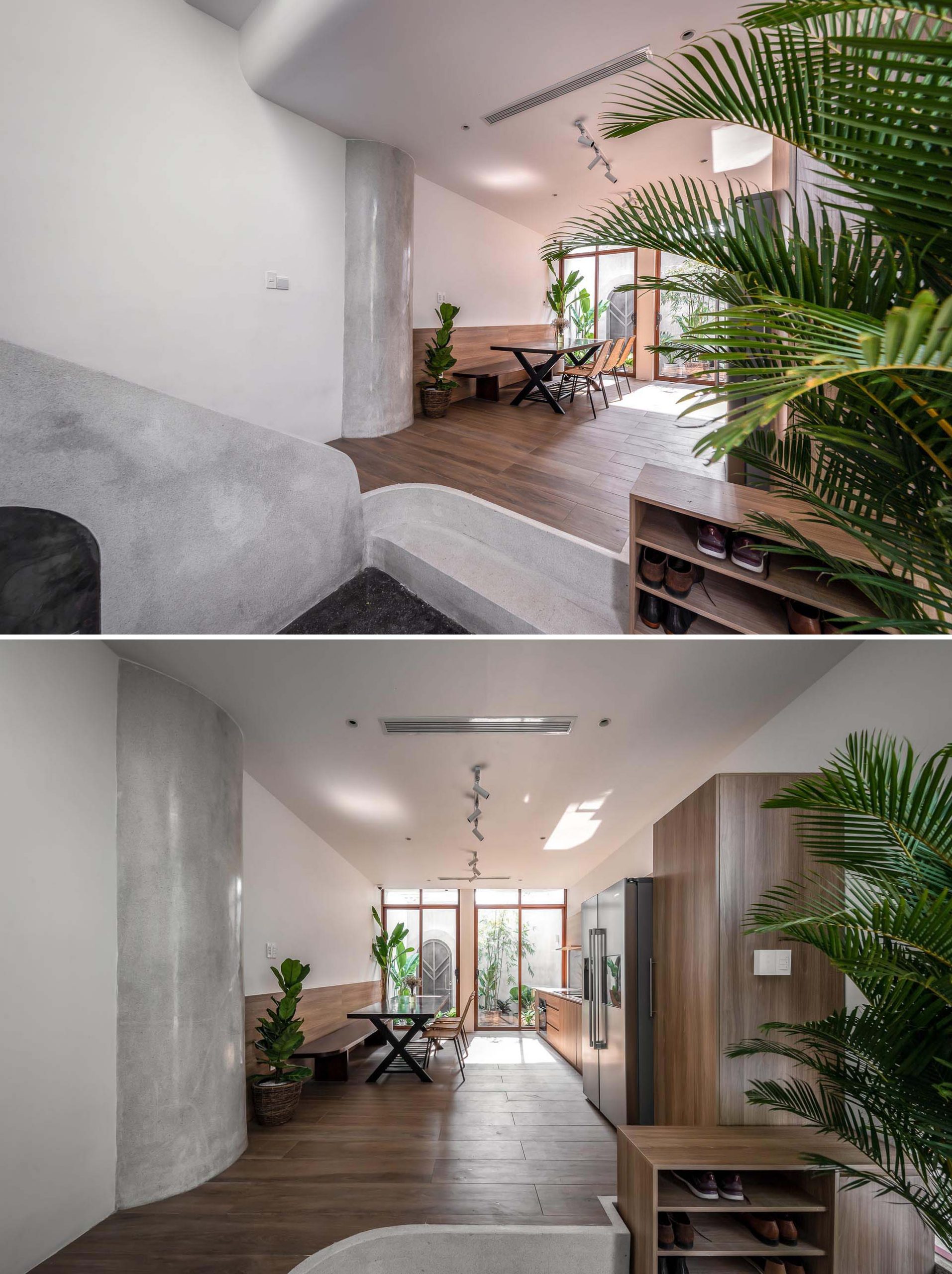 In this modern house, the entryway leads straight into the open plan dining room and kitchen, where wood elements, like the dining bench and kitchen cabinets, complement the natural greenery of the indoor plants.