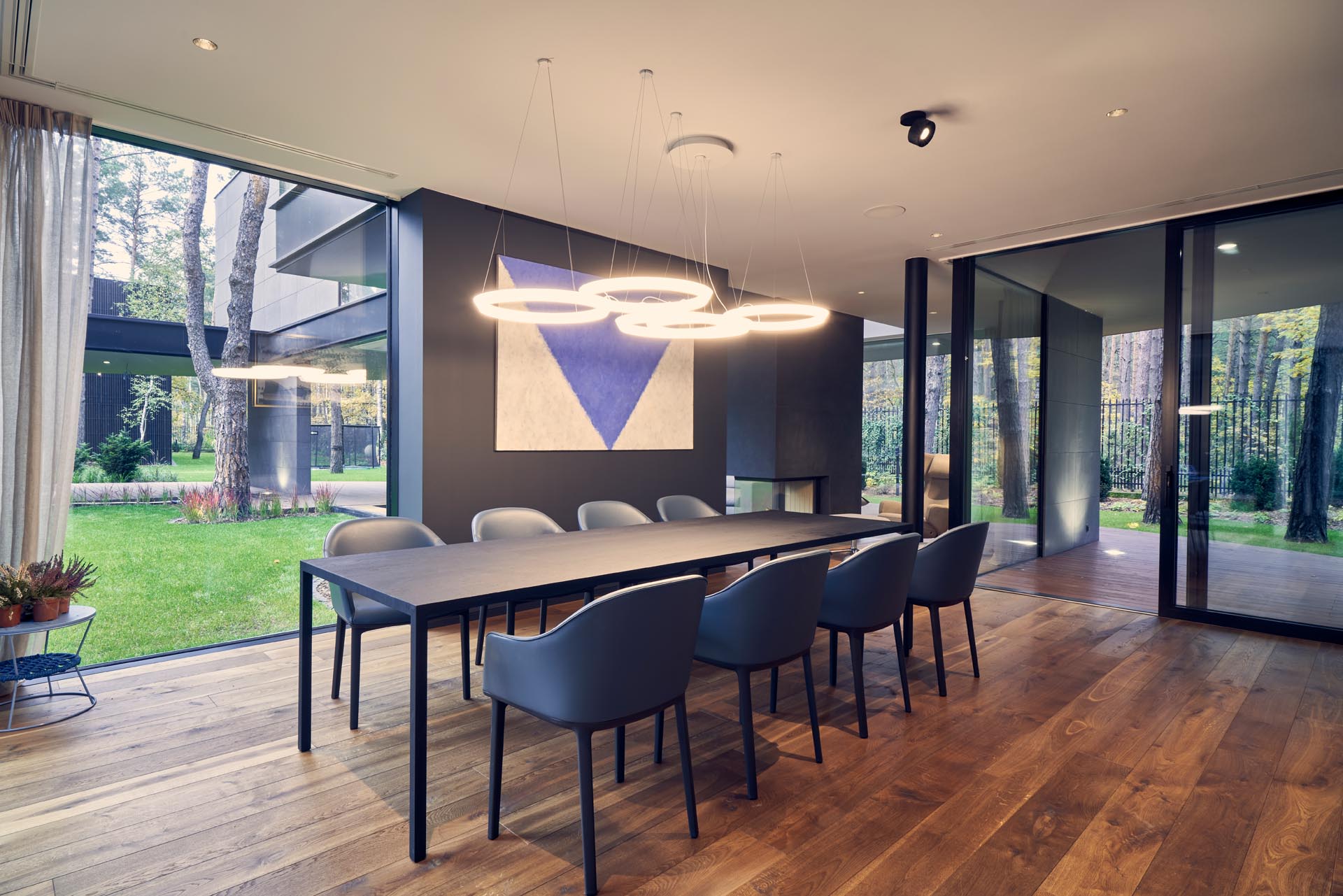 A modern dining room with floor-to-ceiling windows and warm wood floors.