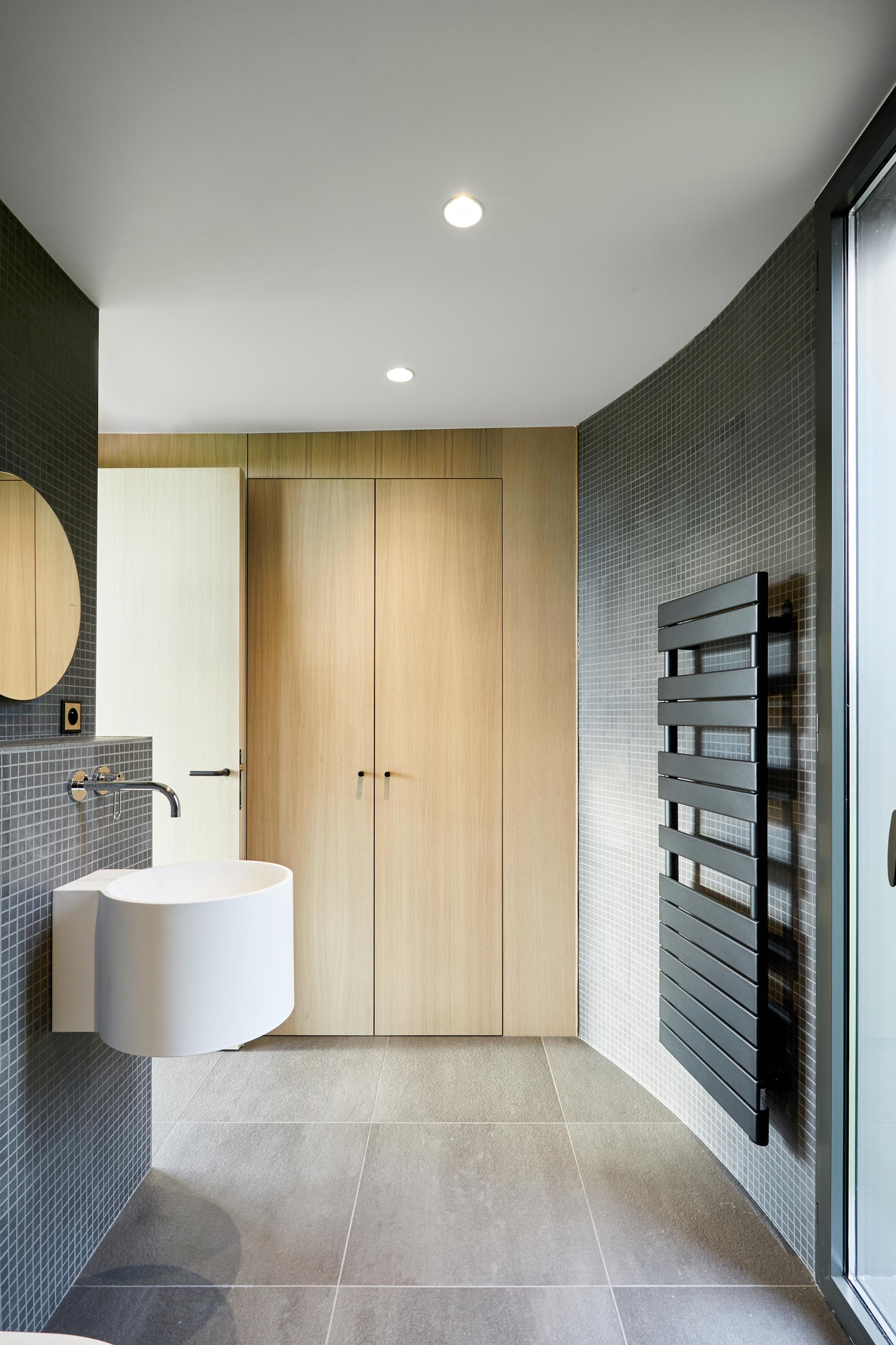 A modern bathroom with walls covered in small square grey tiles.