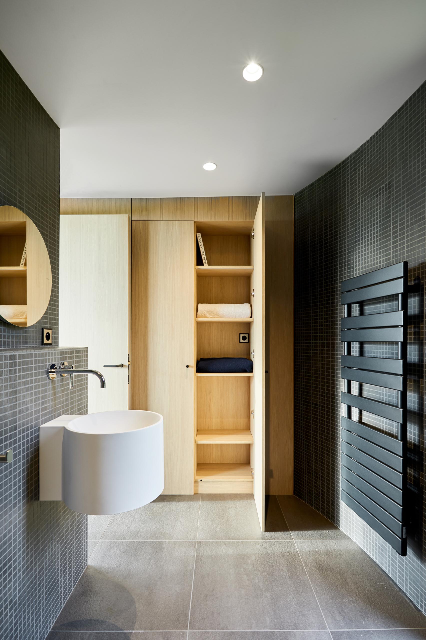 A modern bathroom with walls covered in small square grey tiles.