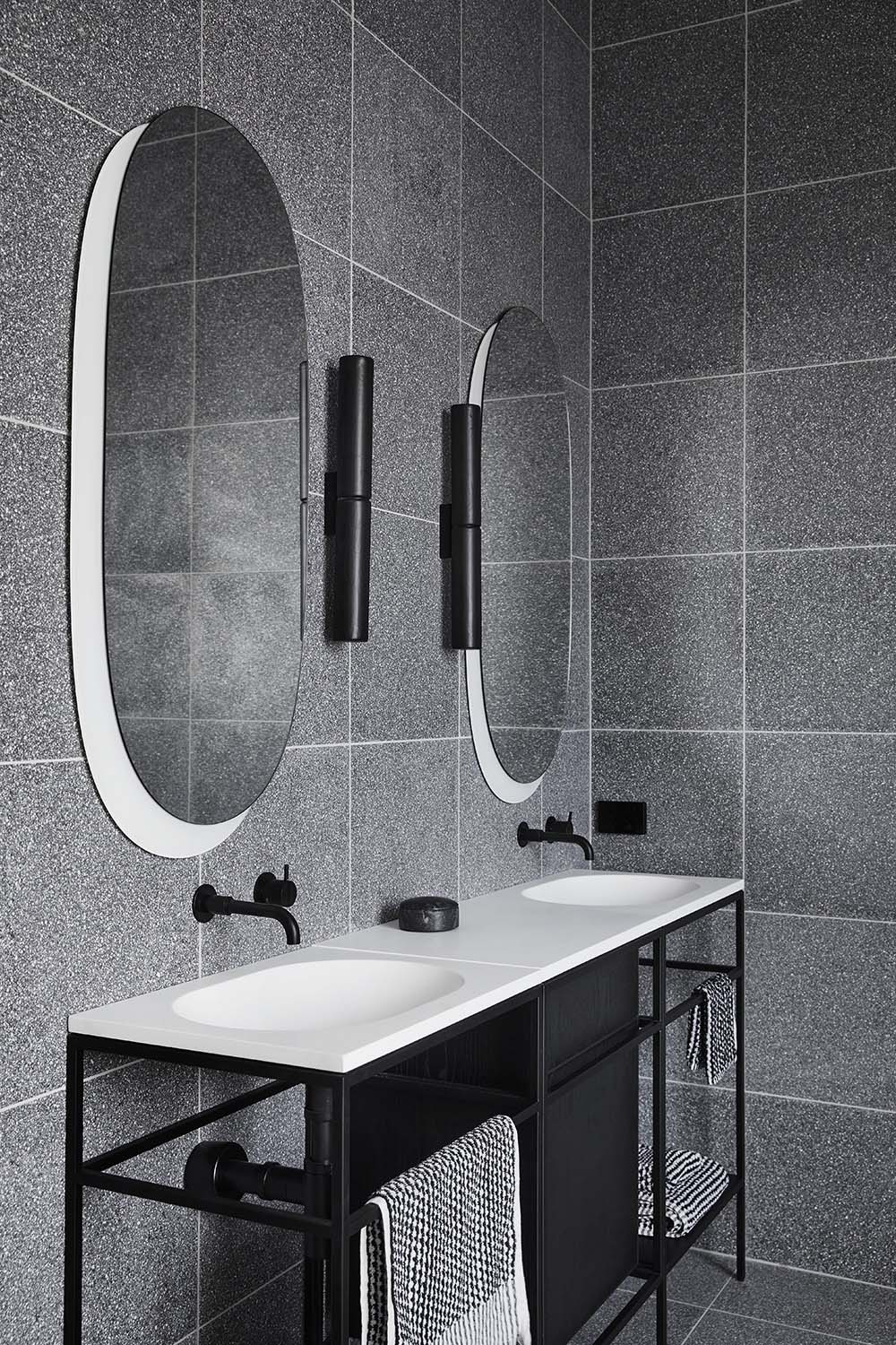 The extremely minimalist and slimline consoles by Ex.t, have black steel frames with white countertops and integrated basins, adding a lightness to the otherwise dark bathrooms.