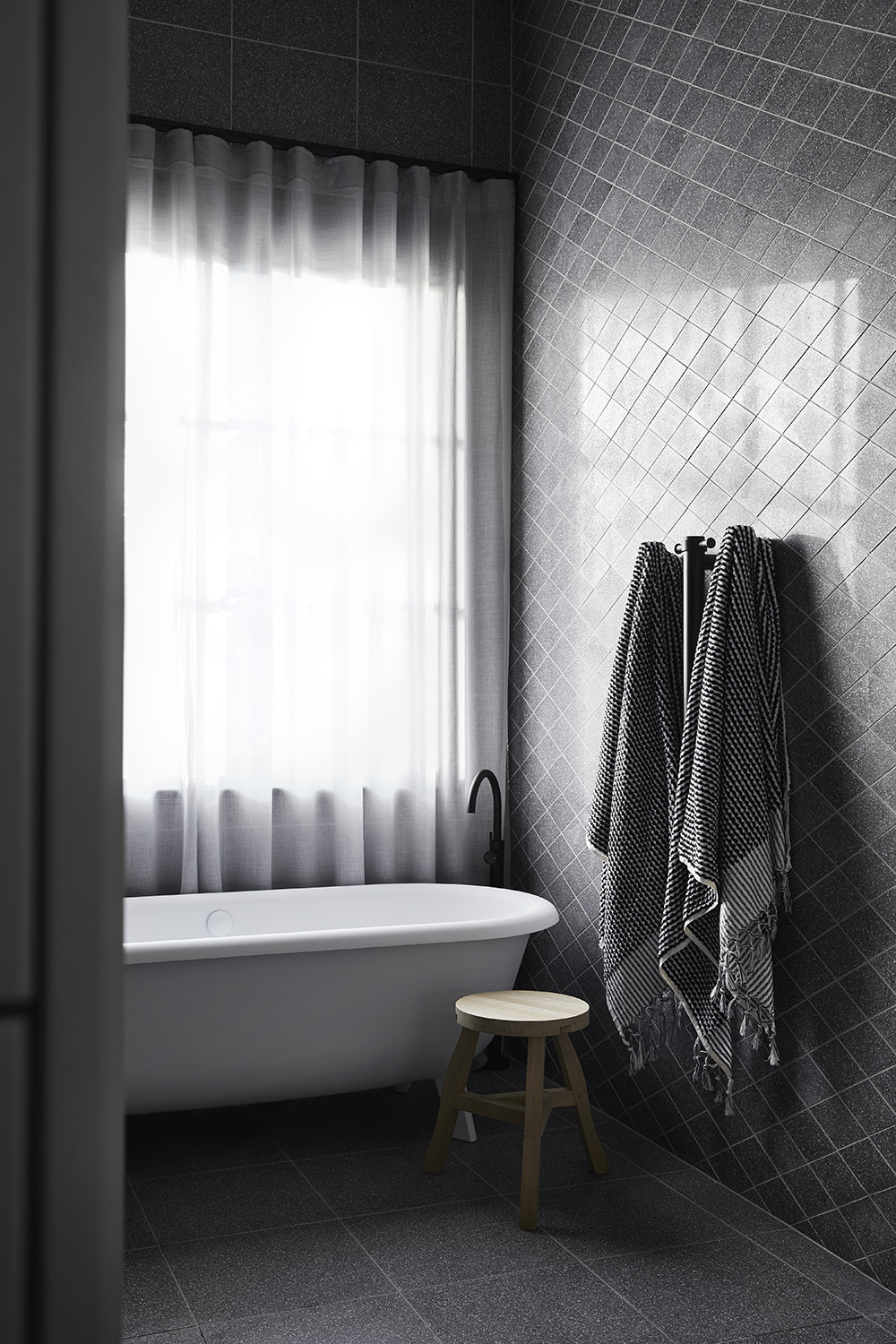 This modern main en-suite bathroom features a wall of custom diamond-cut terrazzo, a geometric shift designed to surprise and relieve the eye, while the Ottocento bath by Agape rests below the window.